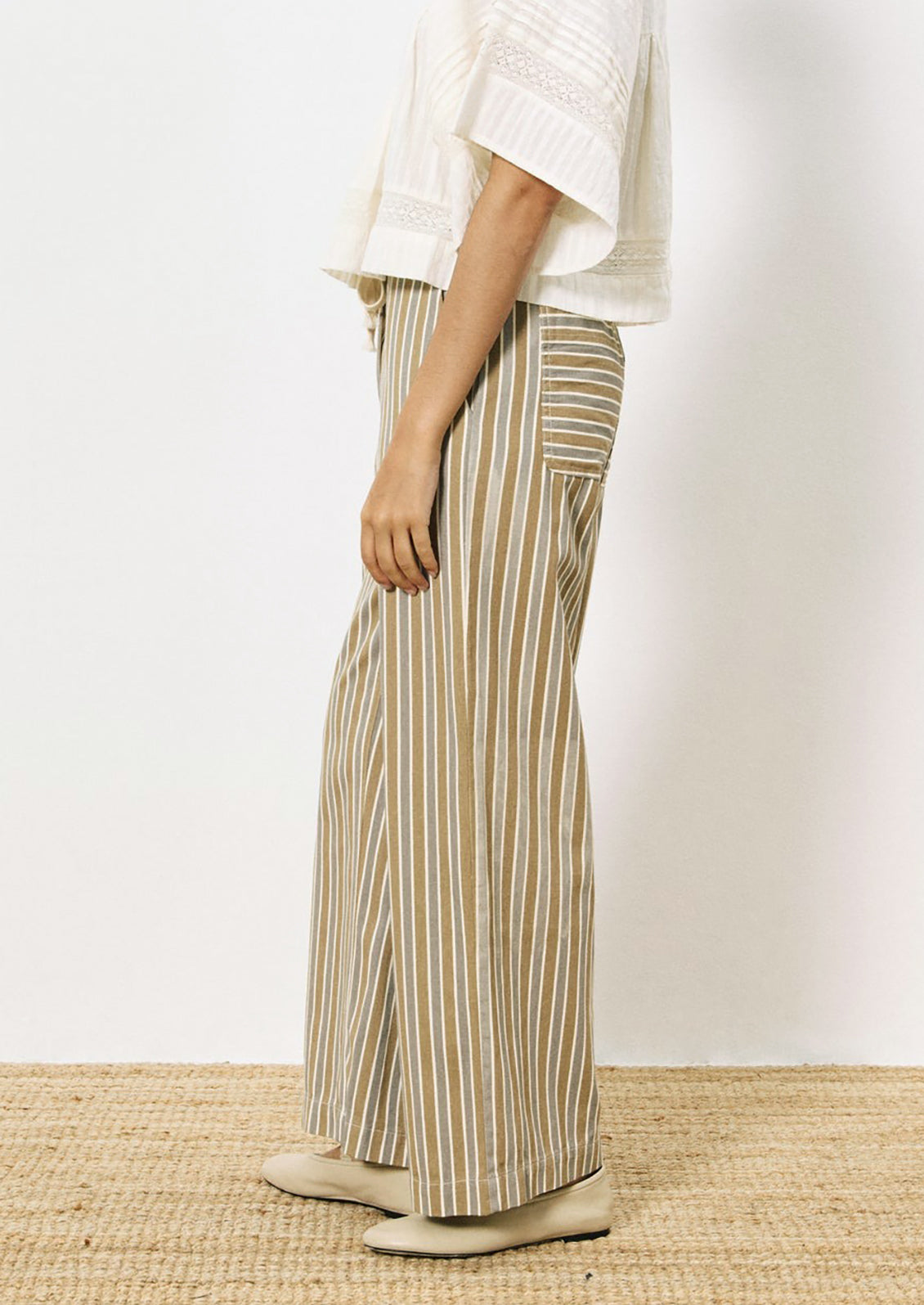 A person wearing a pair of wide leg pants in grey and brown vertical stripe pattern.