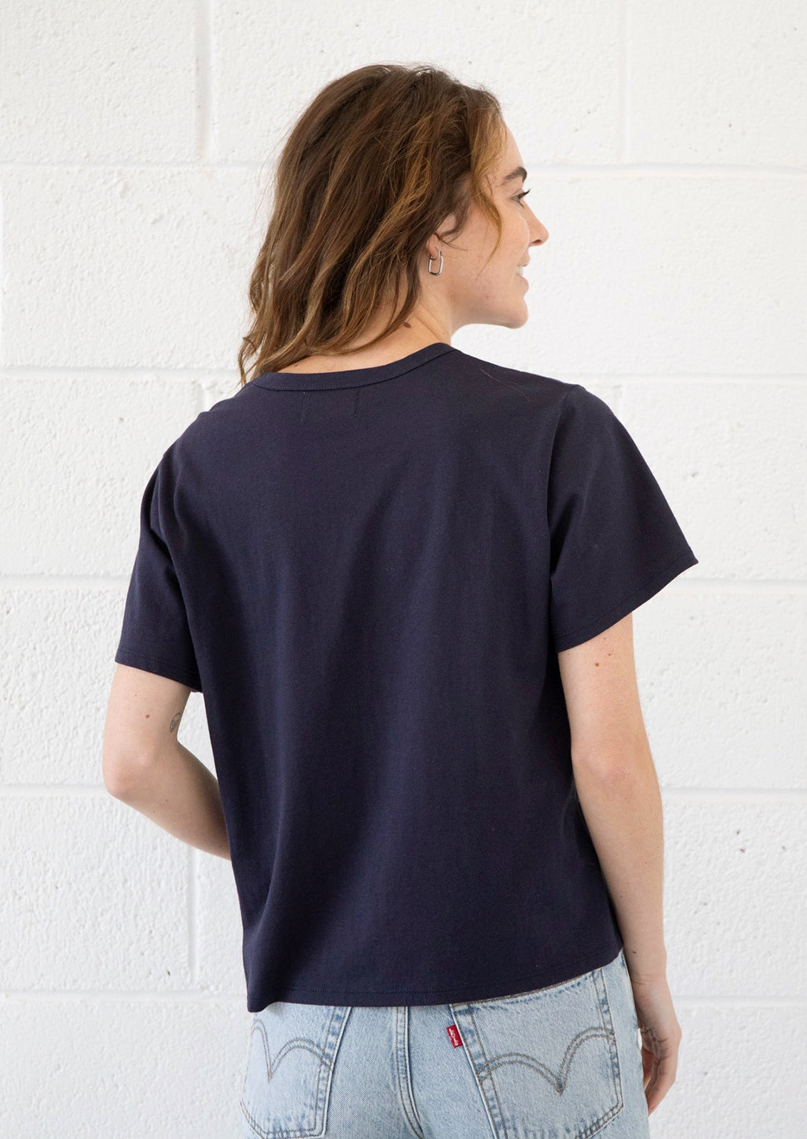 A woman wearing a short sleeve cotton t-shirt in navy blue.