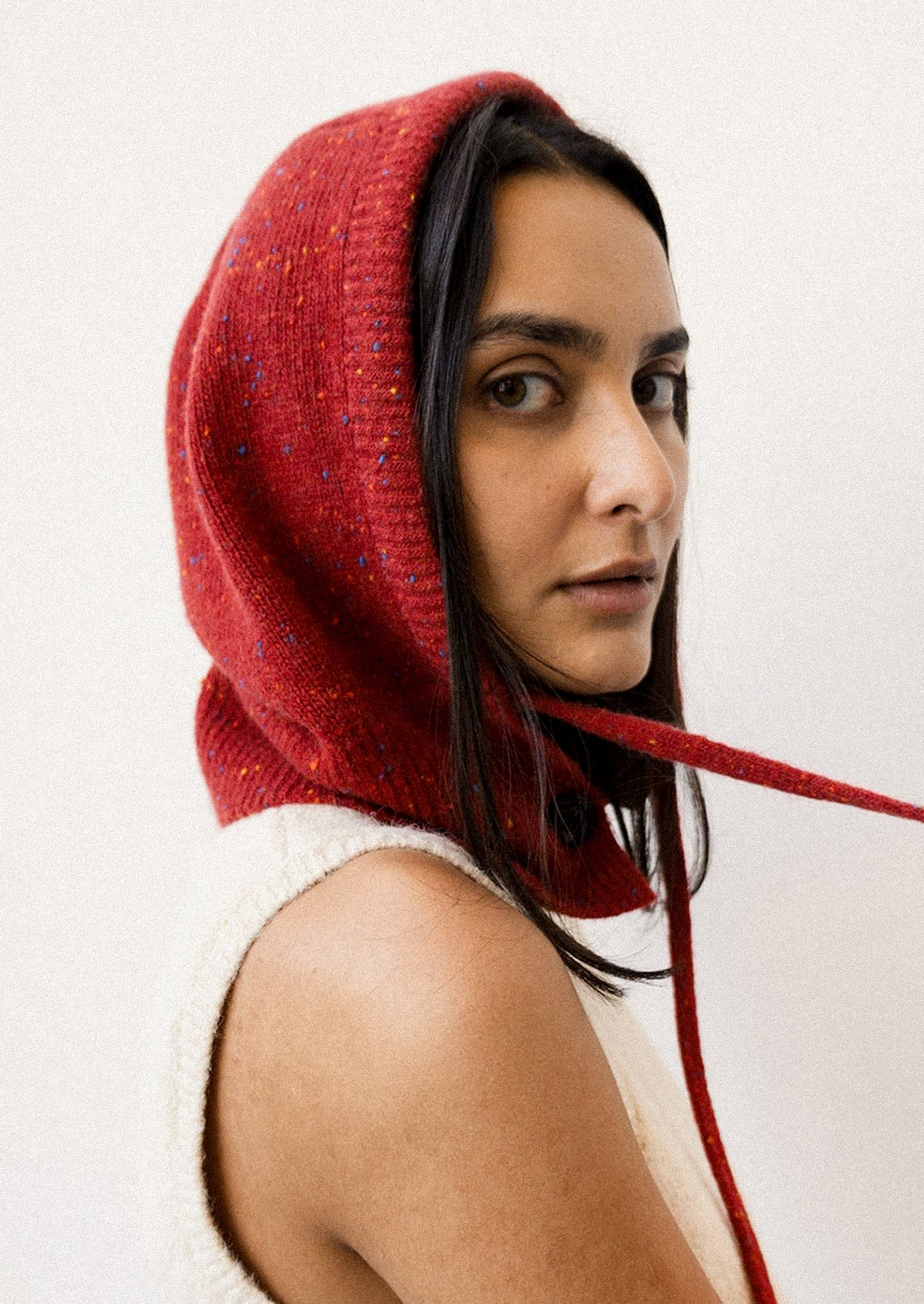 Person wearing a red knitted hood against a white background