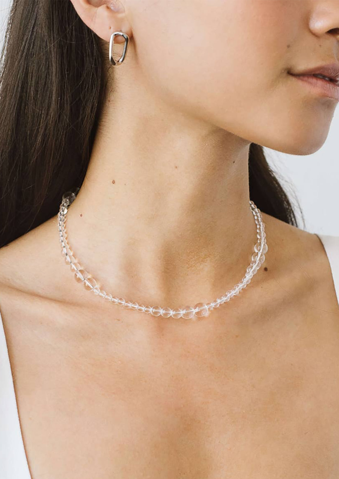 A beaded necklace made of round clear quartz beads in varying sizes.