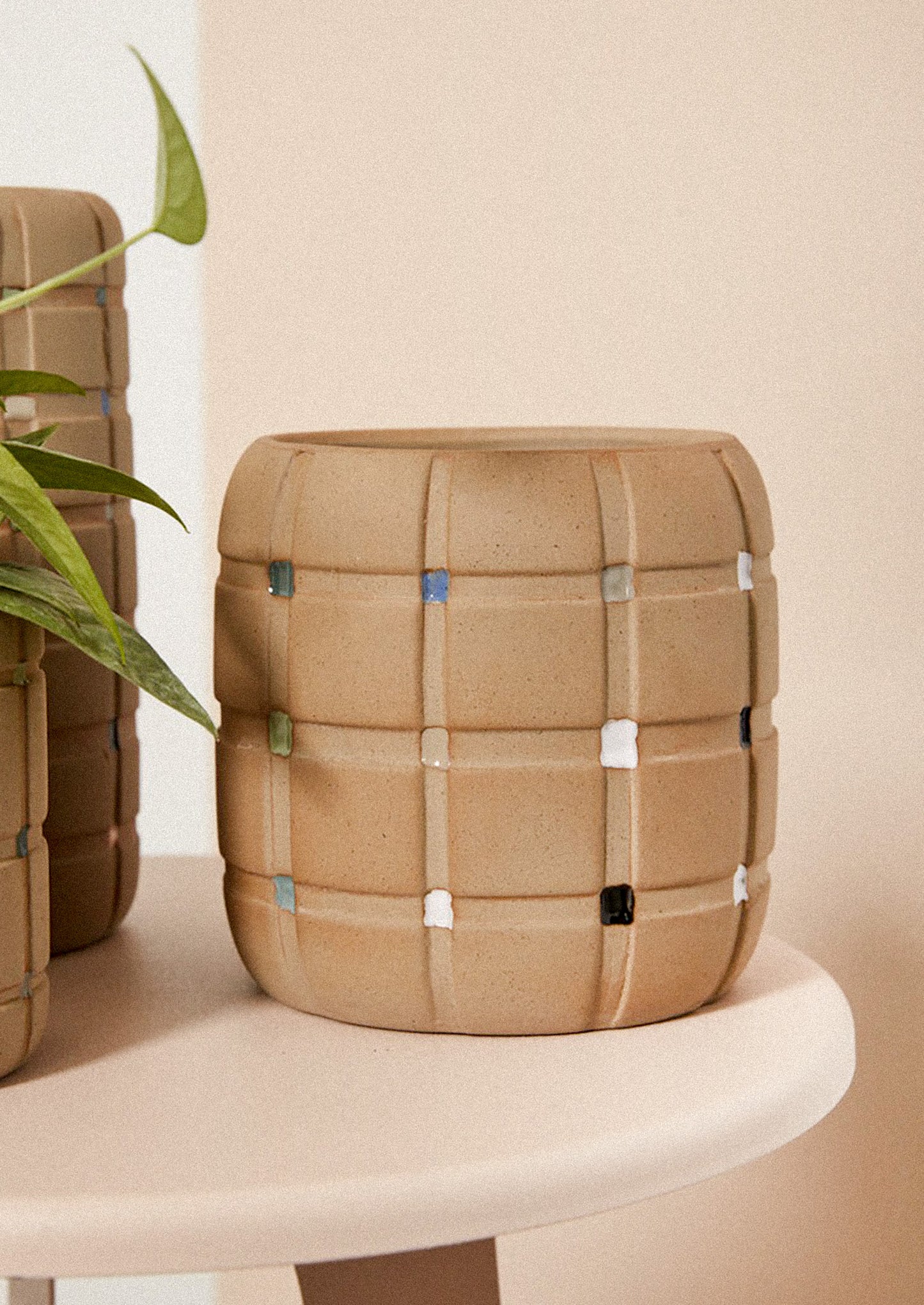 A sand ceramic planter with grid pattern and painted swatches at intersections.