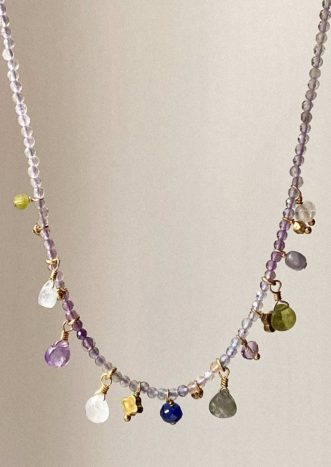 A purple gemstone beaded necklace with assorted gemstone charms.