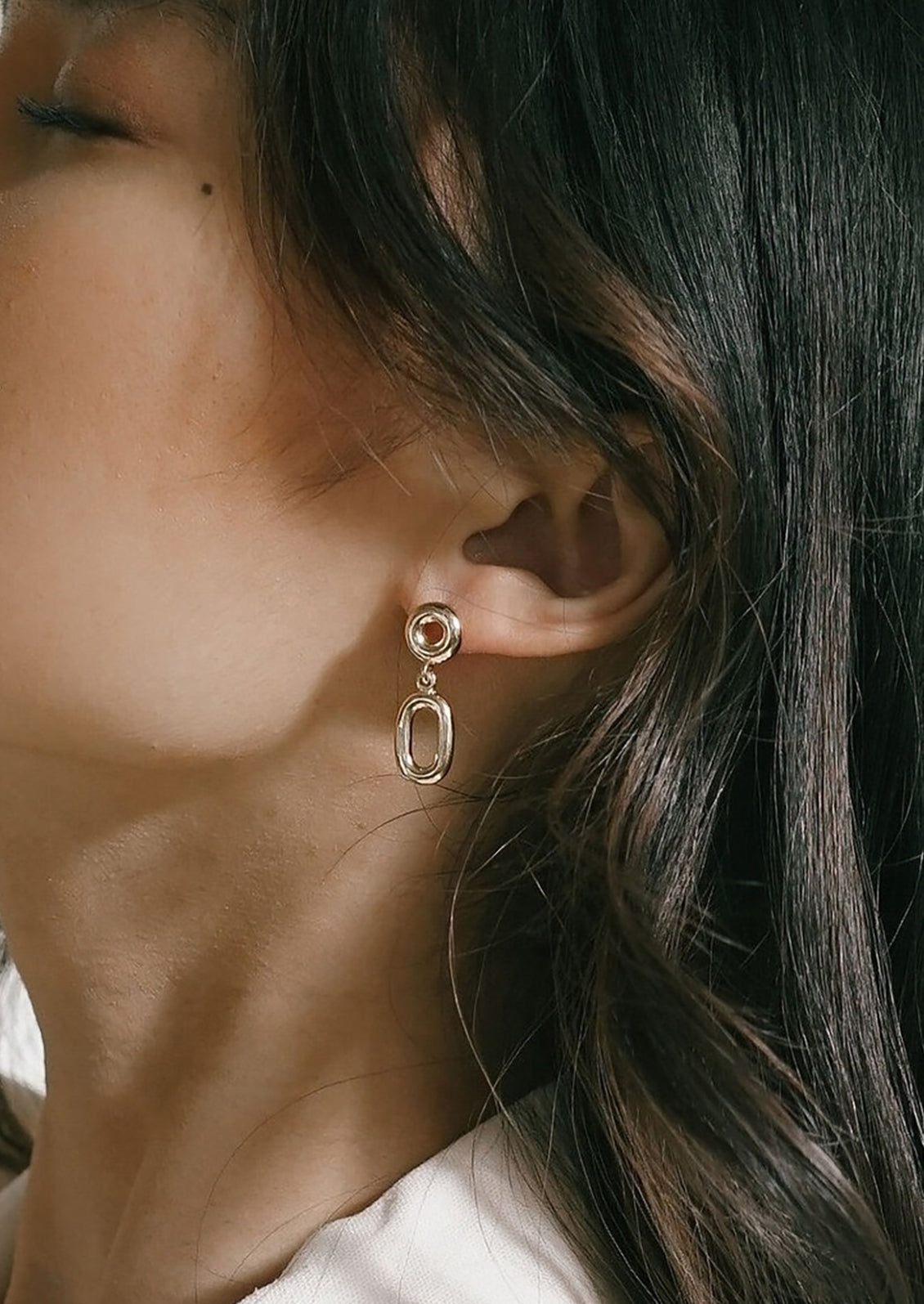 A pair of gold earrings with hollow circle and oval shapes.