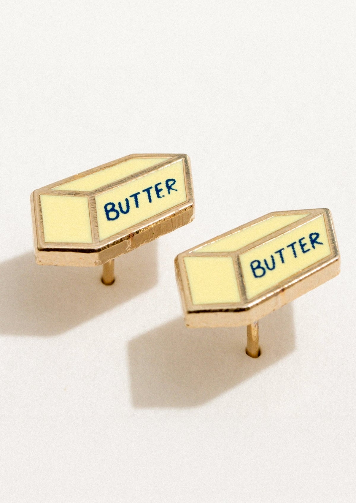 A pair of enamel stud earrings in the shape of a stick of butter.
