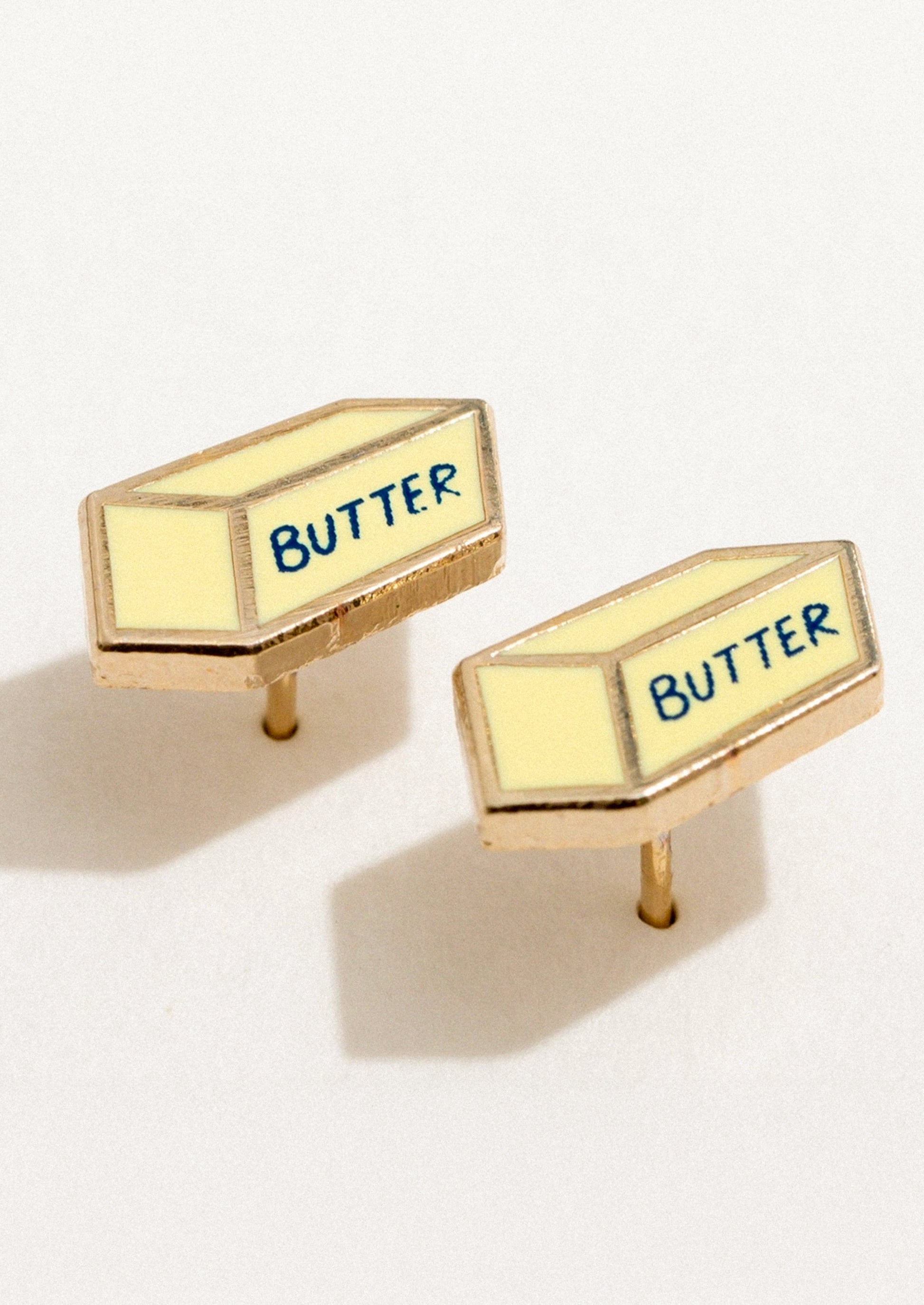 A pair of enamel stud earrings in the shape of a stick of butter.