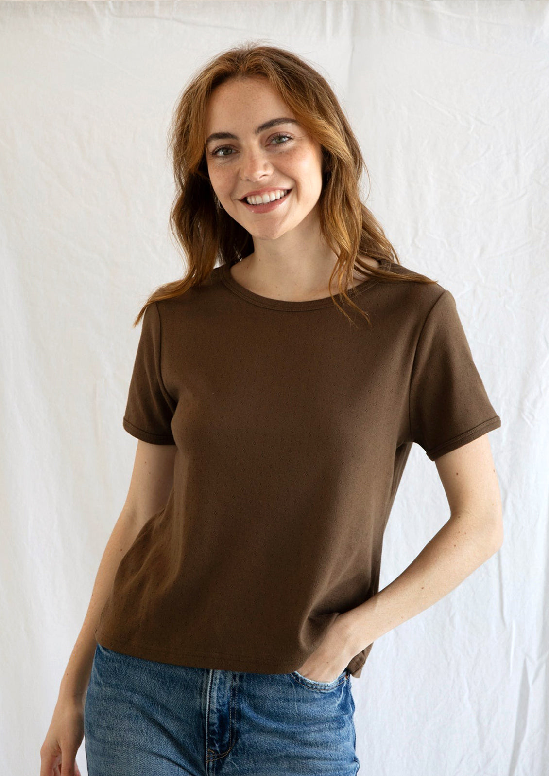 A woman wearing a pointelle stitch t-shirt in chocolate brown color.