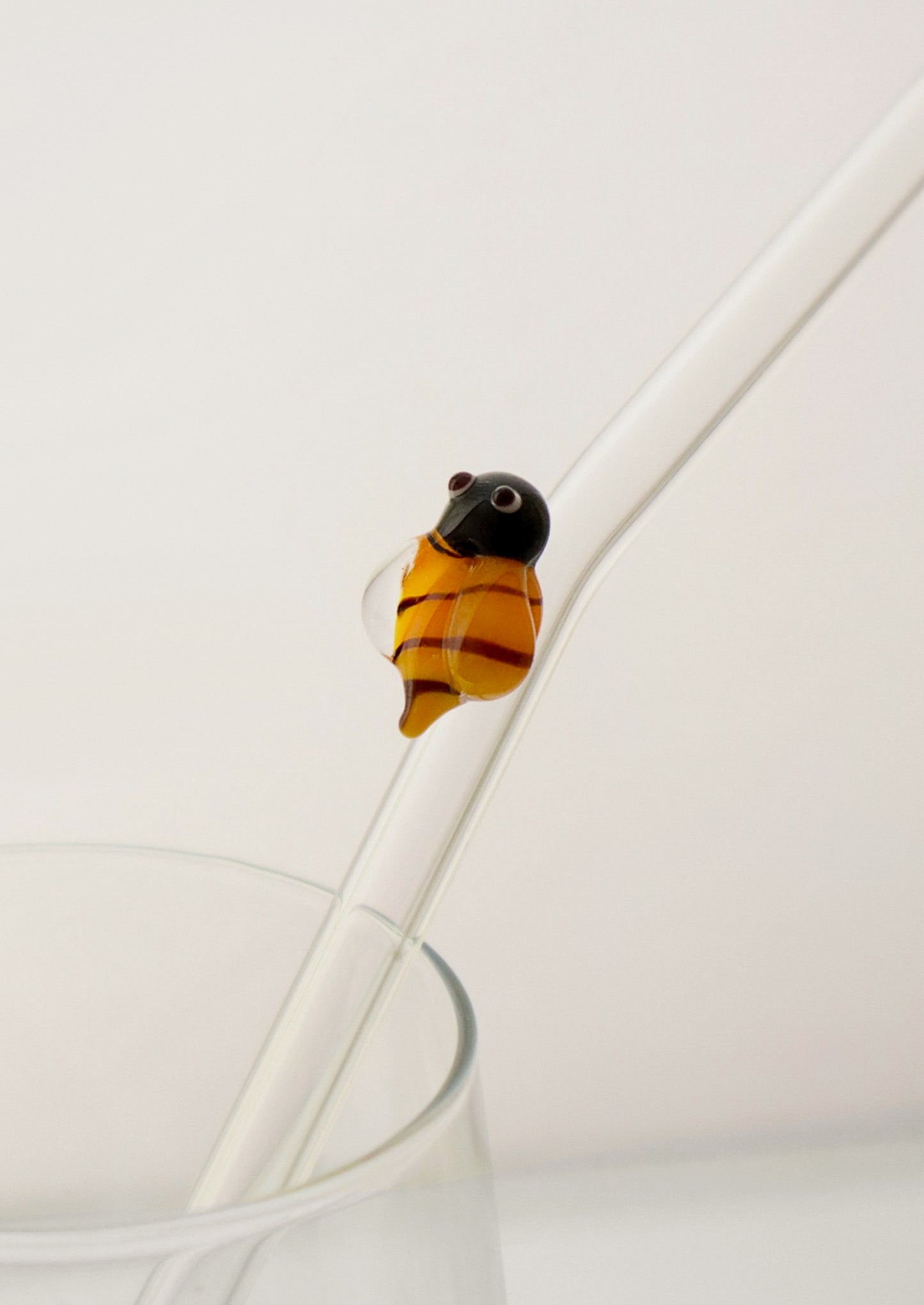 A clear glass straws with bent shape, with lampwork bee figurine.