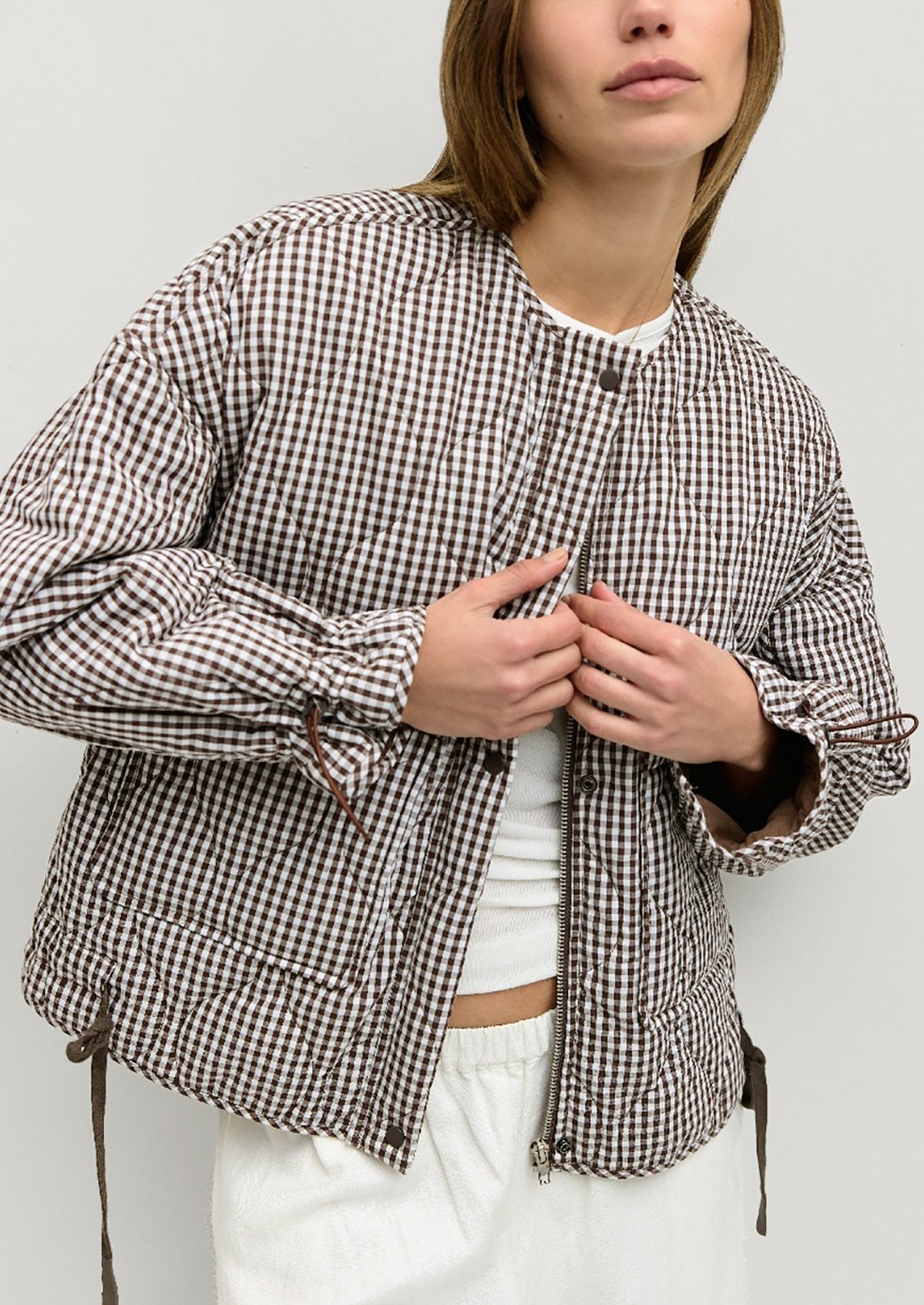 A woman wearing a quilted jacket in chocolate brown and white gingham.