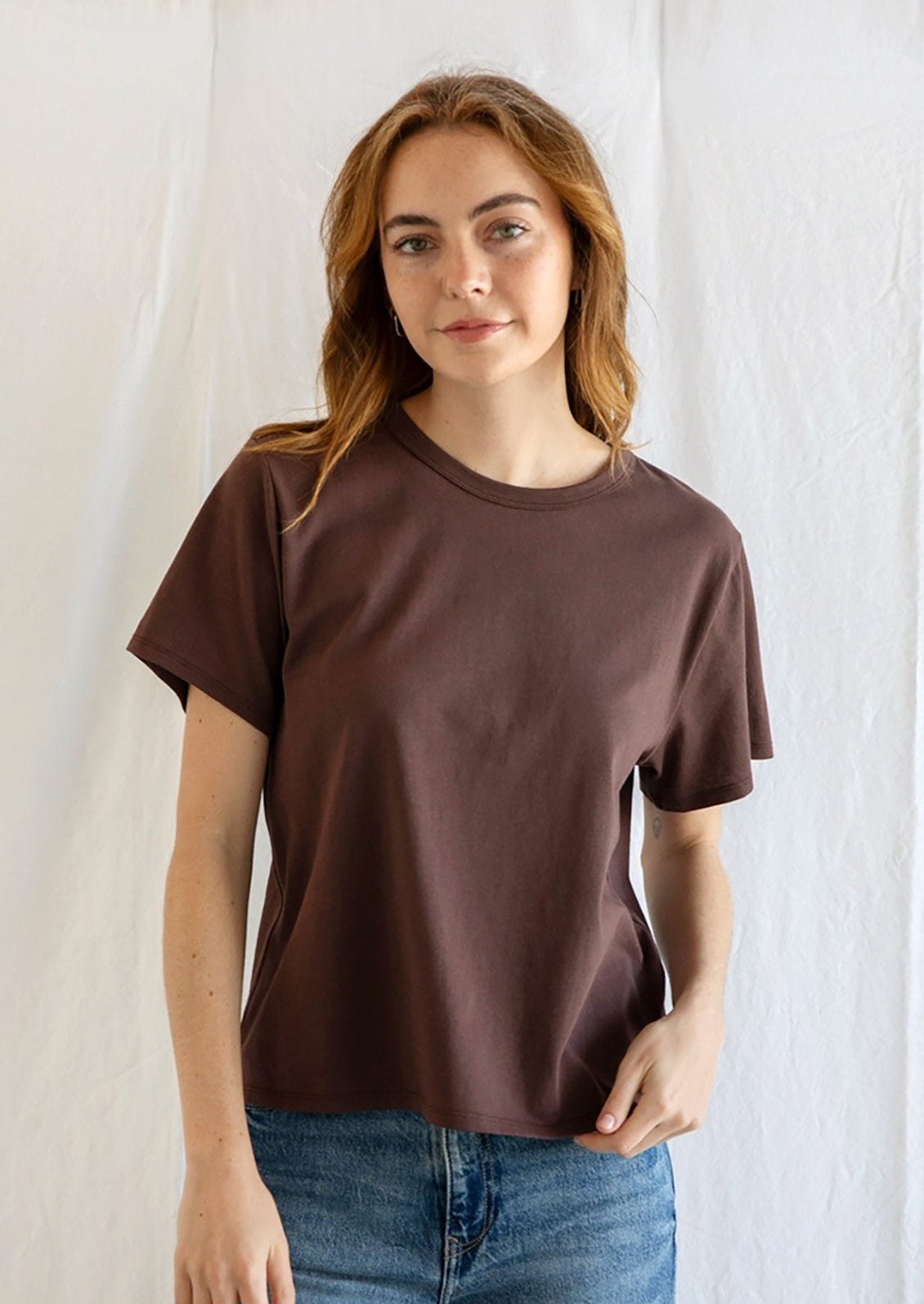 A woman wearing a short sleeve cotton t-shirt in chocolate brown.