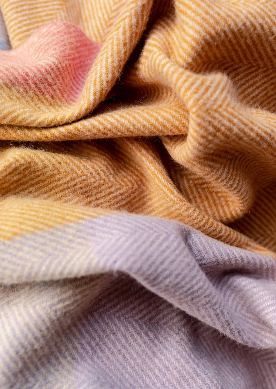 A colorful check patterned blanket in blue, orange, cream and pink tones.