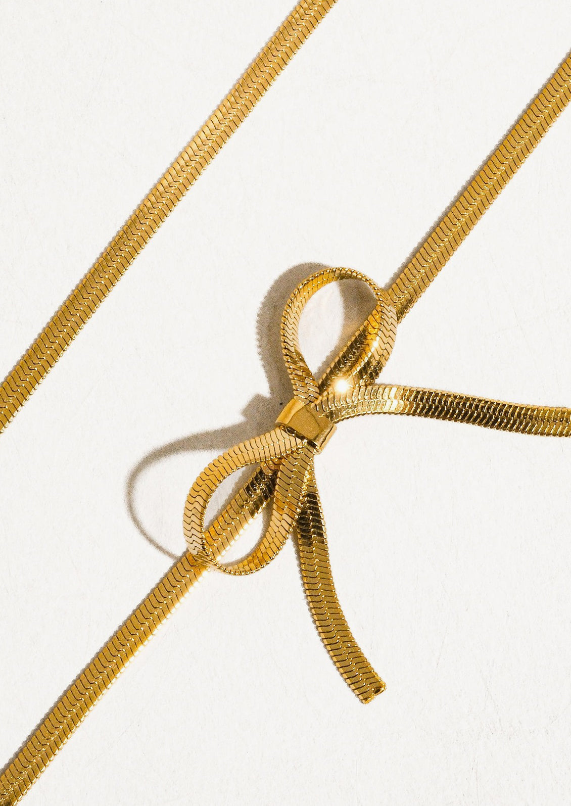 A gold choker-style necklace with bow shape at front.