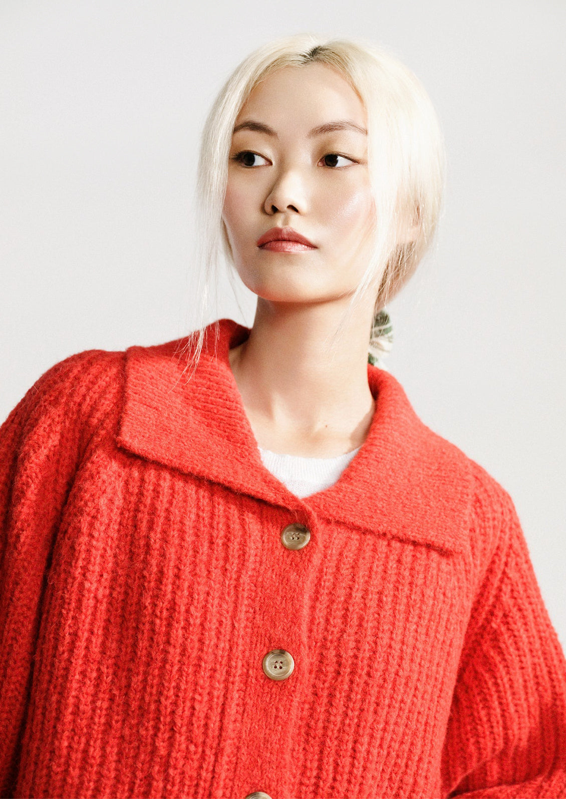A woman wearing a red-orange knit cardigan sweater.