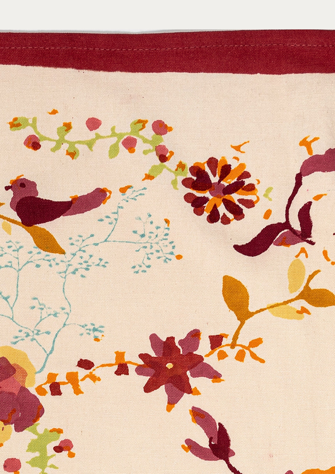 Close-up of a floral patterned fabric with birds and flowers on a beige background.