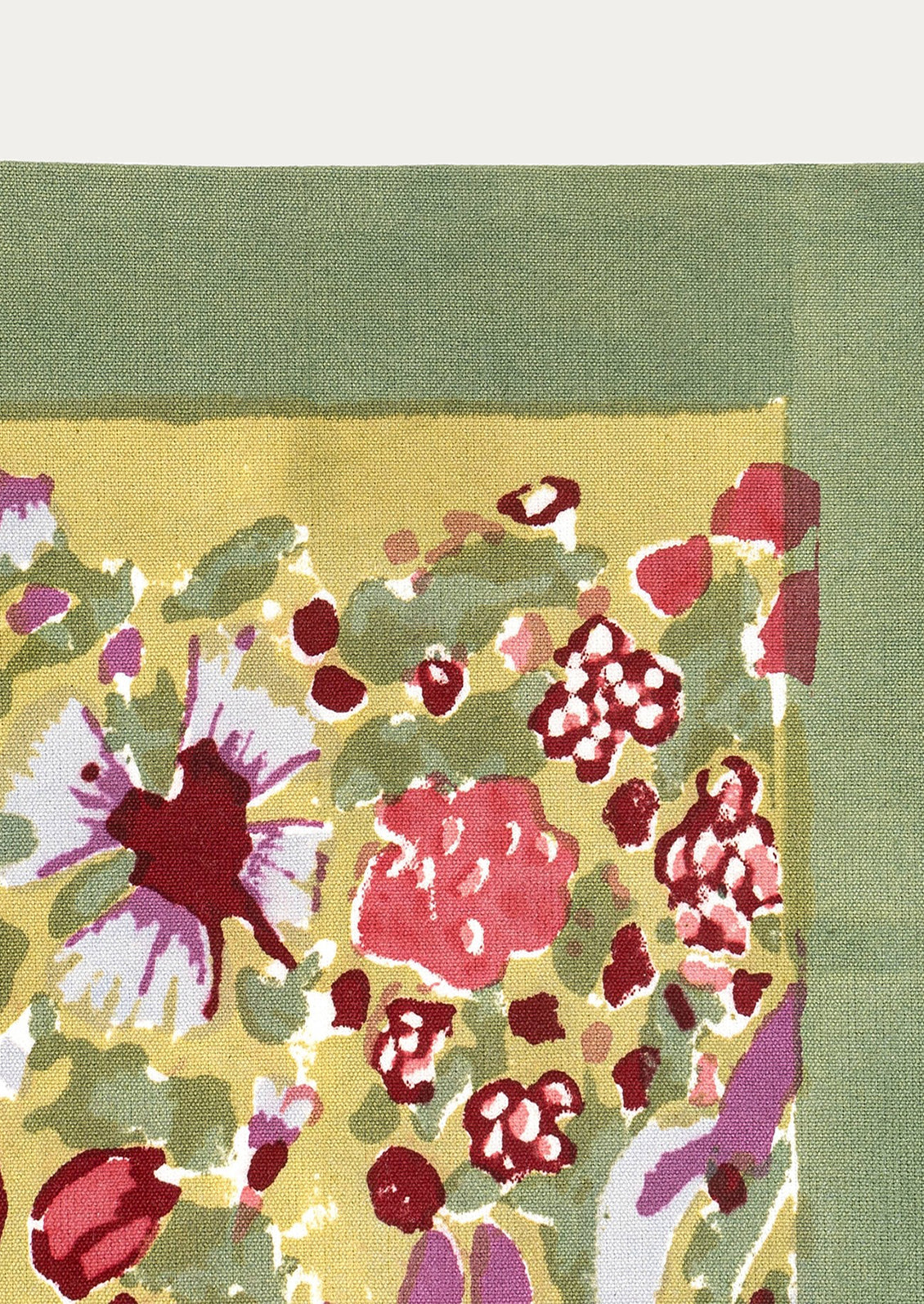 A block printed placemat with olive green border, and red, green and purple floral print on mustard at center.