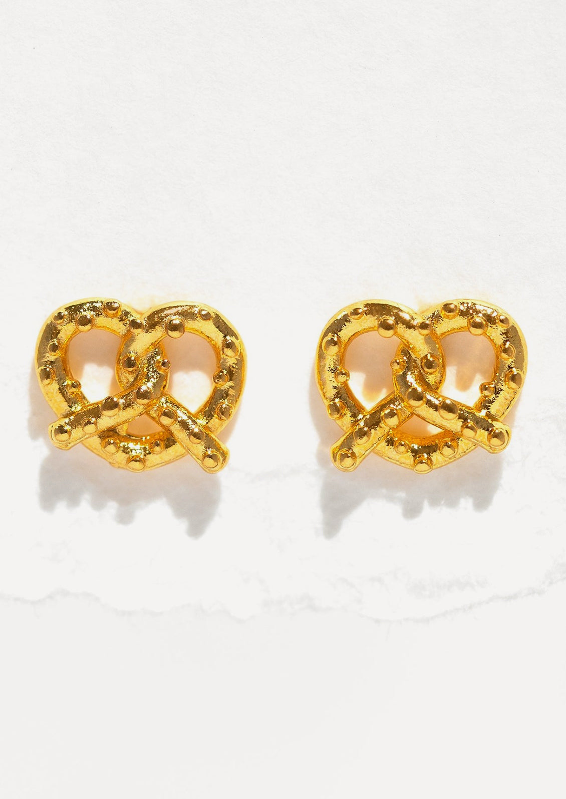 A pair of gold stud earrings in the shape of a pretzel.