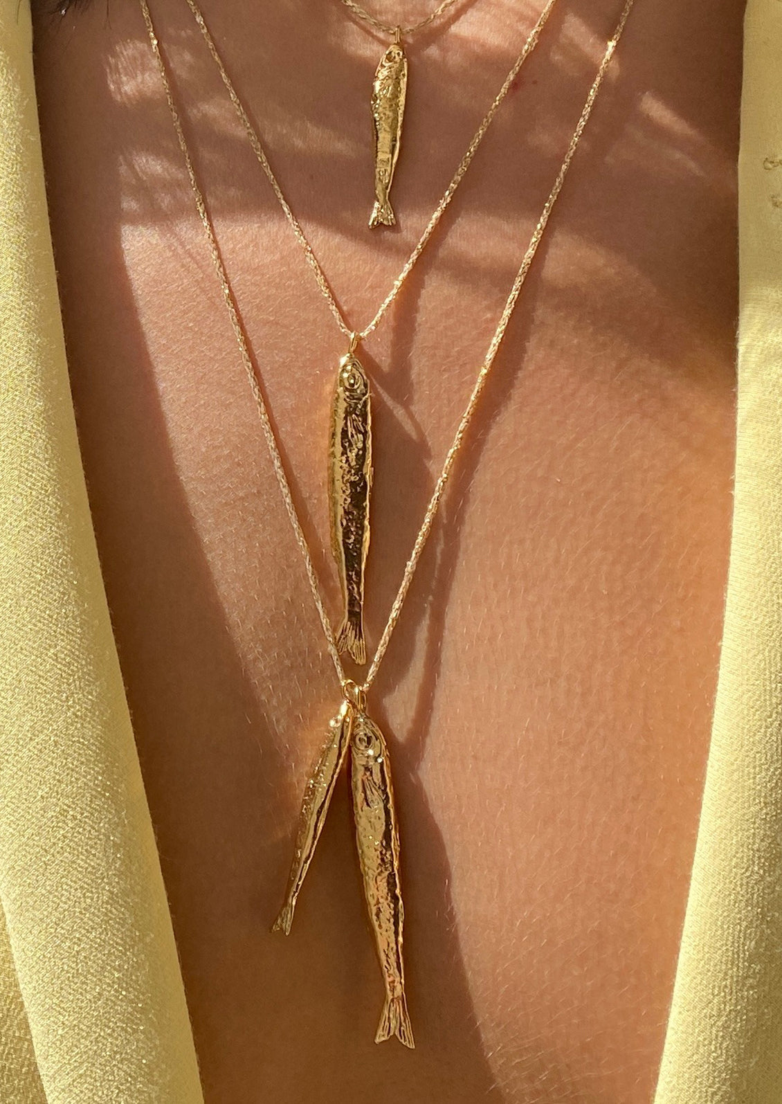 A necklace on gold string with two fish charms.