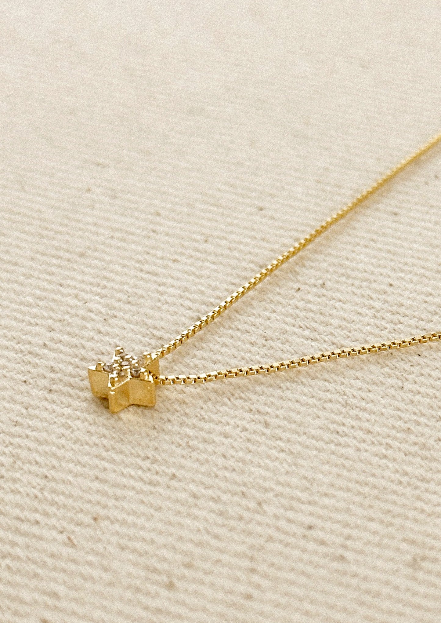 A gold box chain necklace with small gold & crystal star charm.
