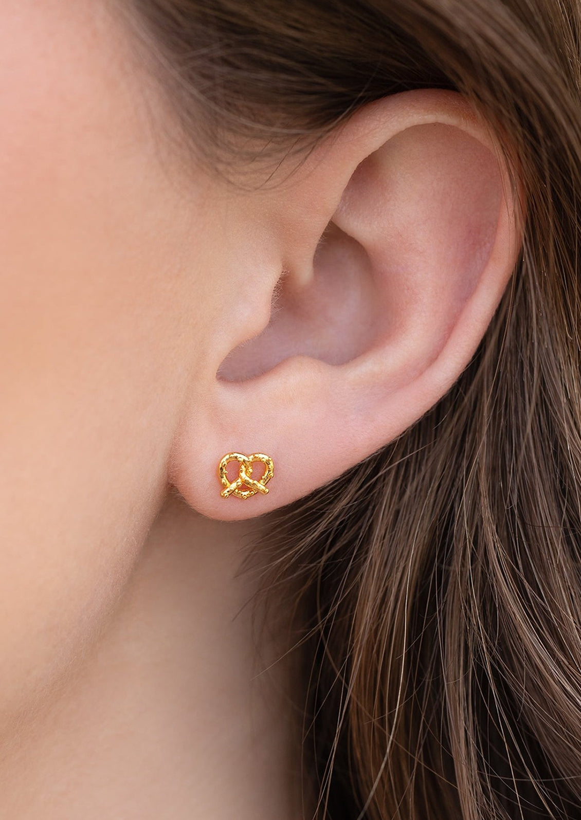 A pair of gold stud earrings in the shape of a pretzel.