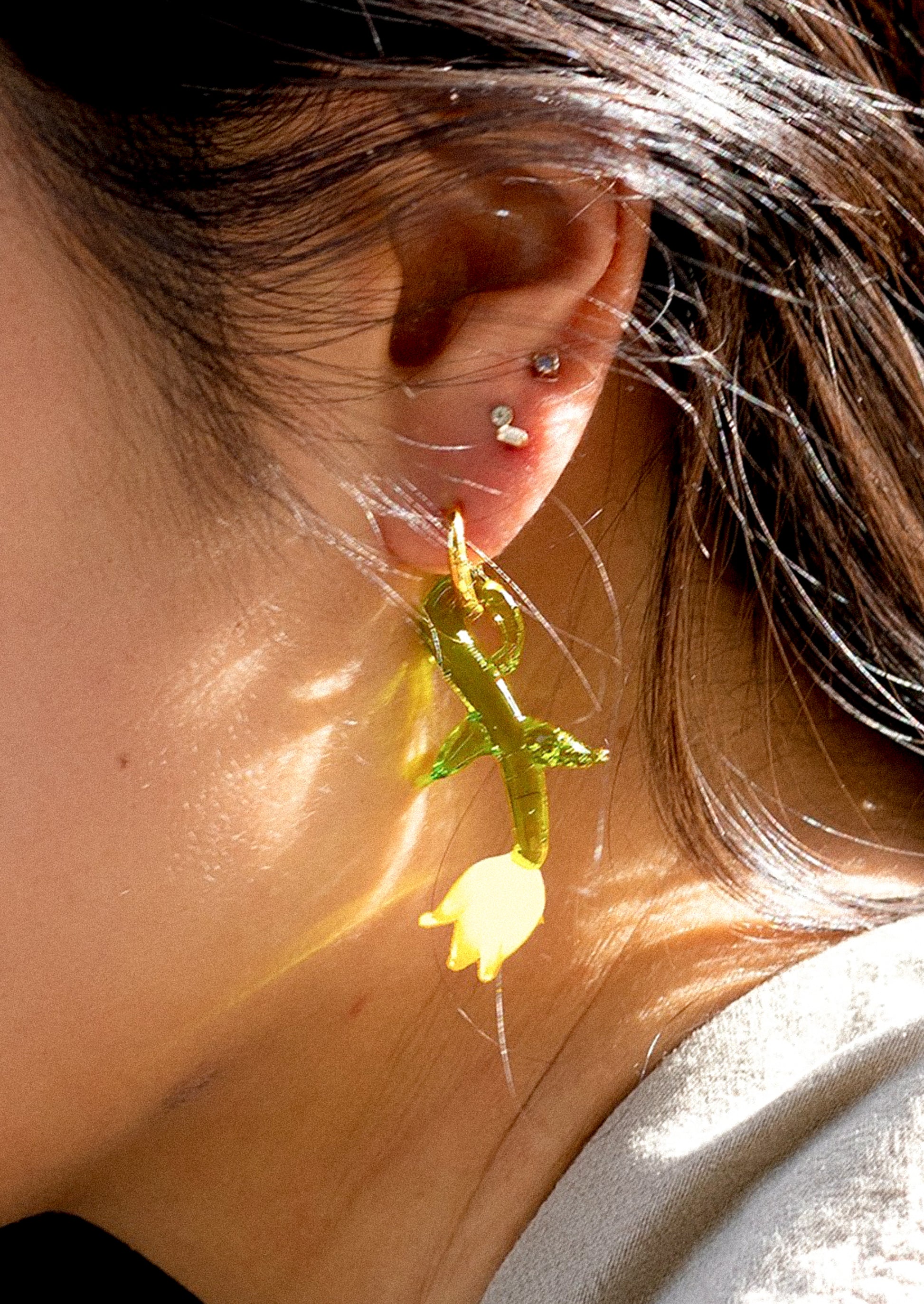 A pair of gold hoop earrings with murano glass yellow tulip charm.