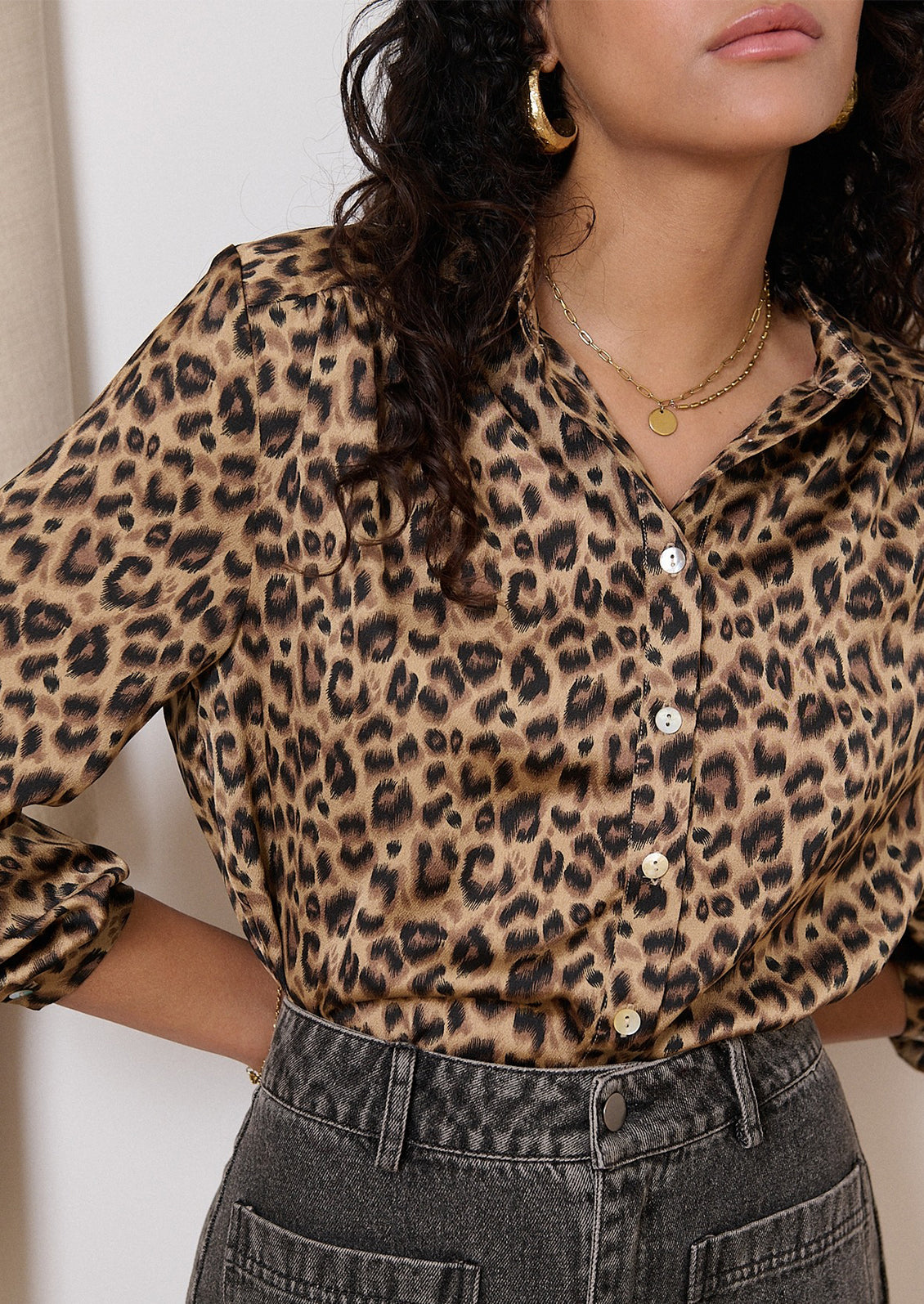 A woman wearing a long sleeve leopard print collared shirt.