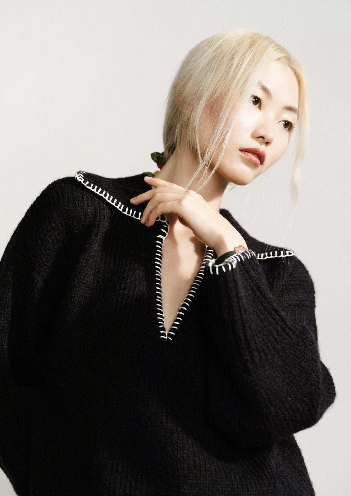 A woman wearing a black sweater with notched collared v-neckline and wide bell sleeves.