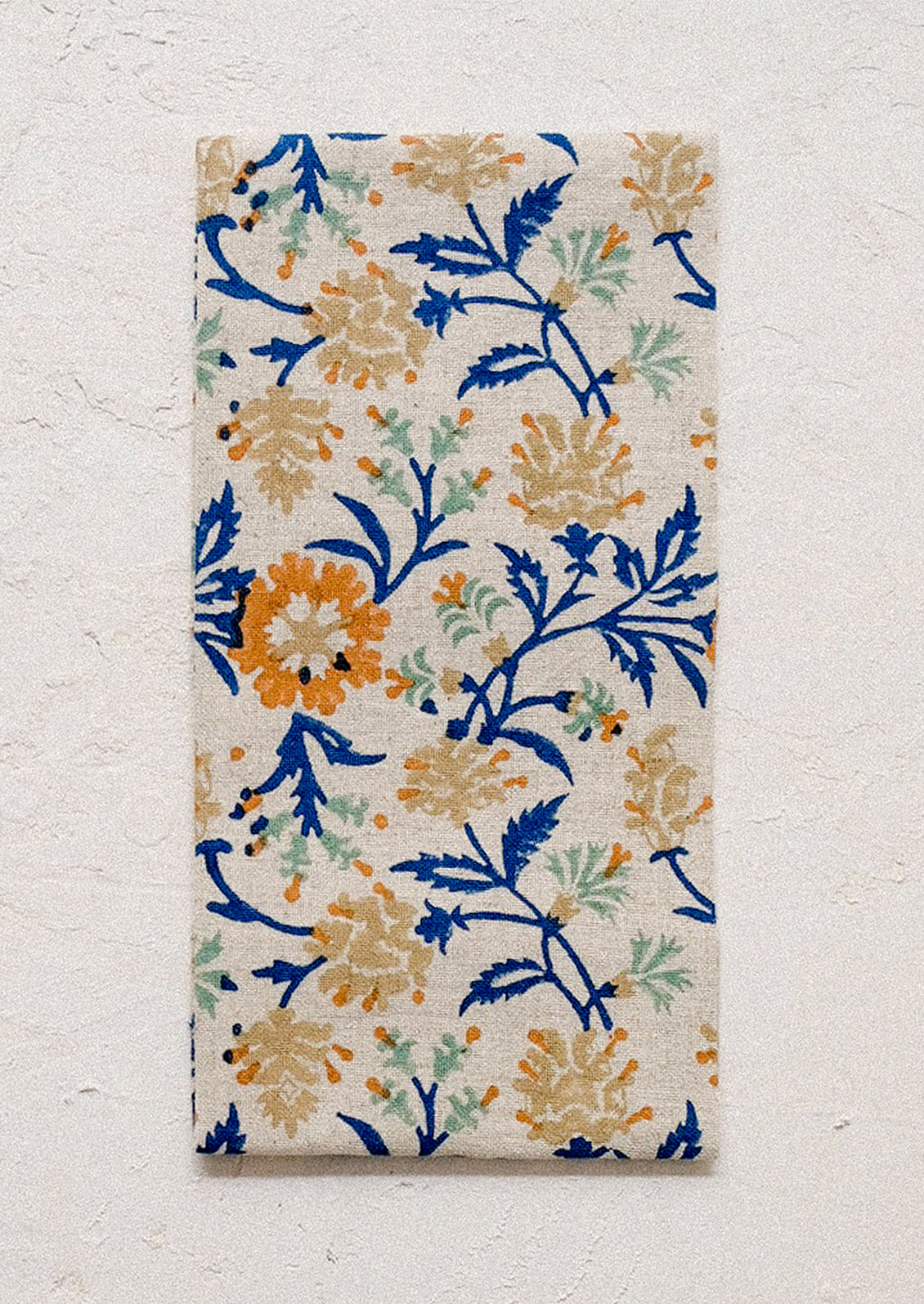 A linen napkin with blue and orange color floral print.