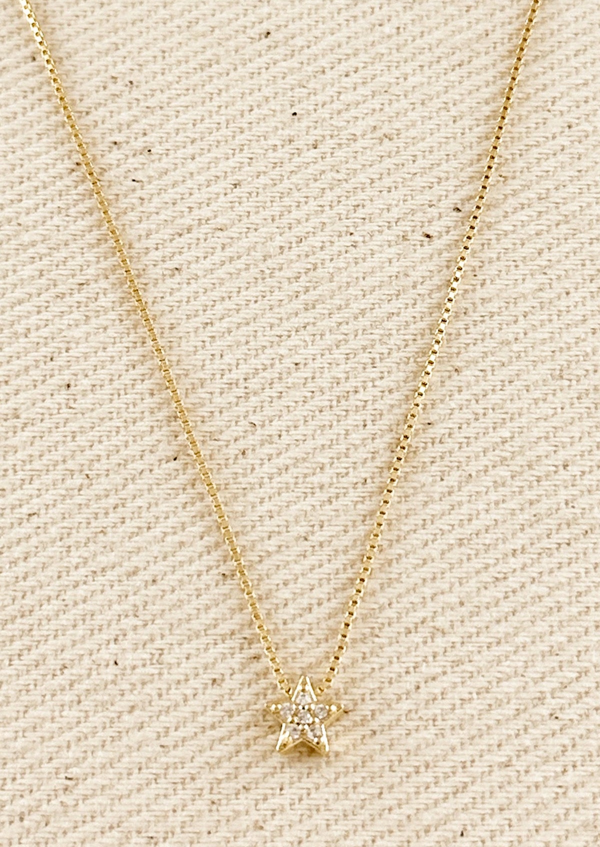 A gold box chain necklace with small gold & crystal star charm.