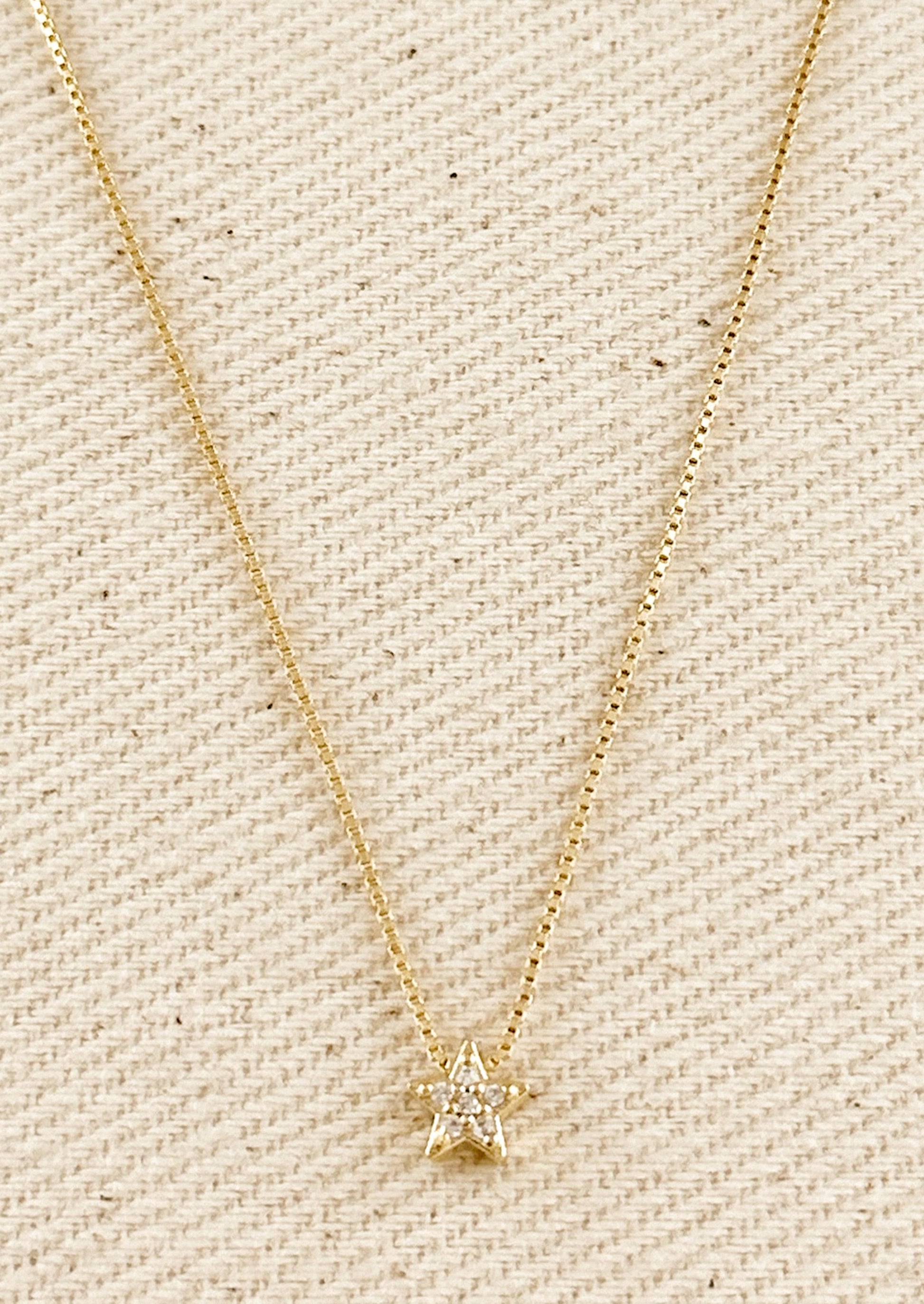 A gold box chain necklace with small gold & crystal star charm.