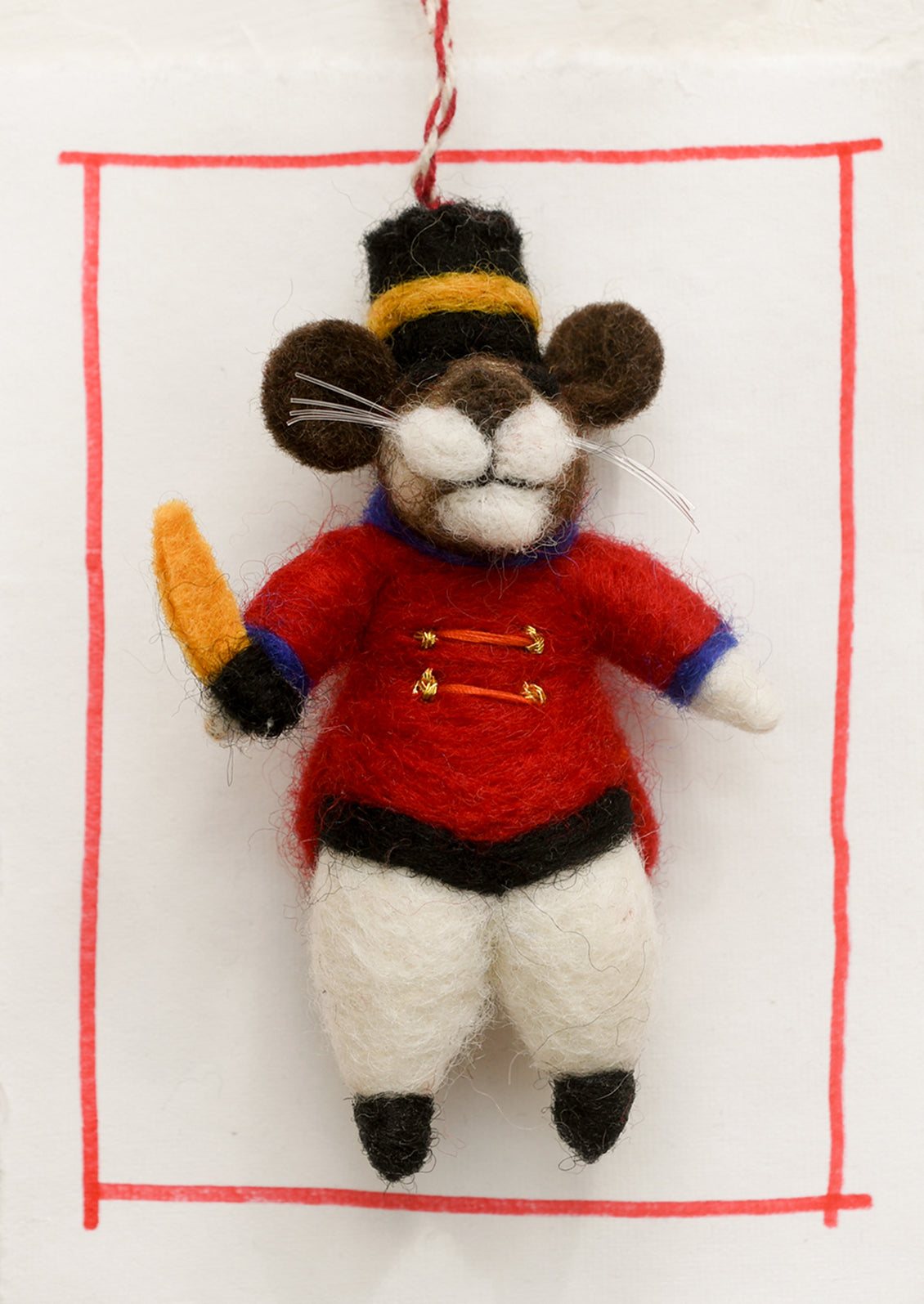 A felted wool ornament of mouse in drum major costume.
