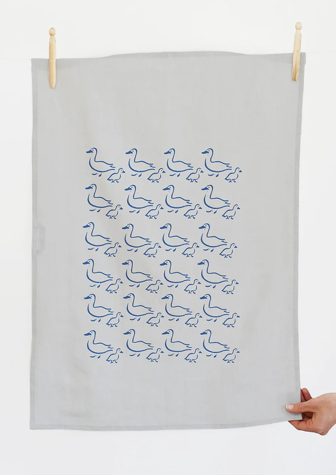 A grey linen tea towel with blue duck illustration print.