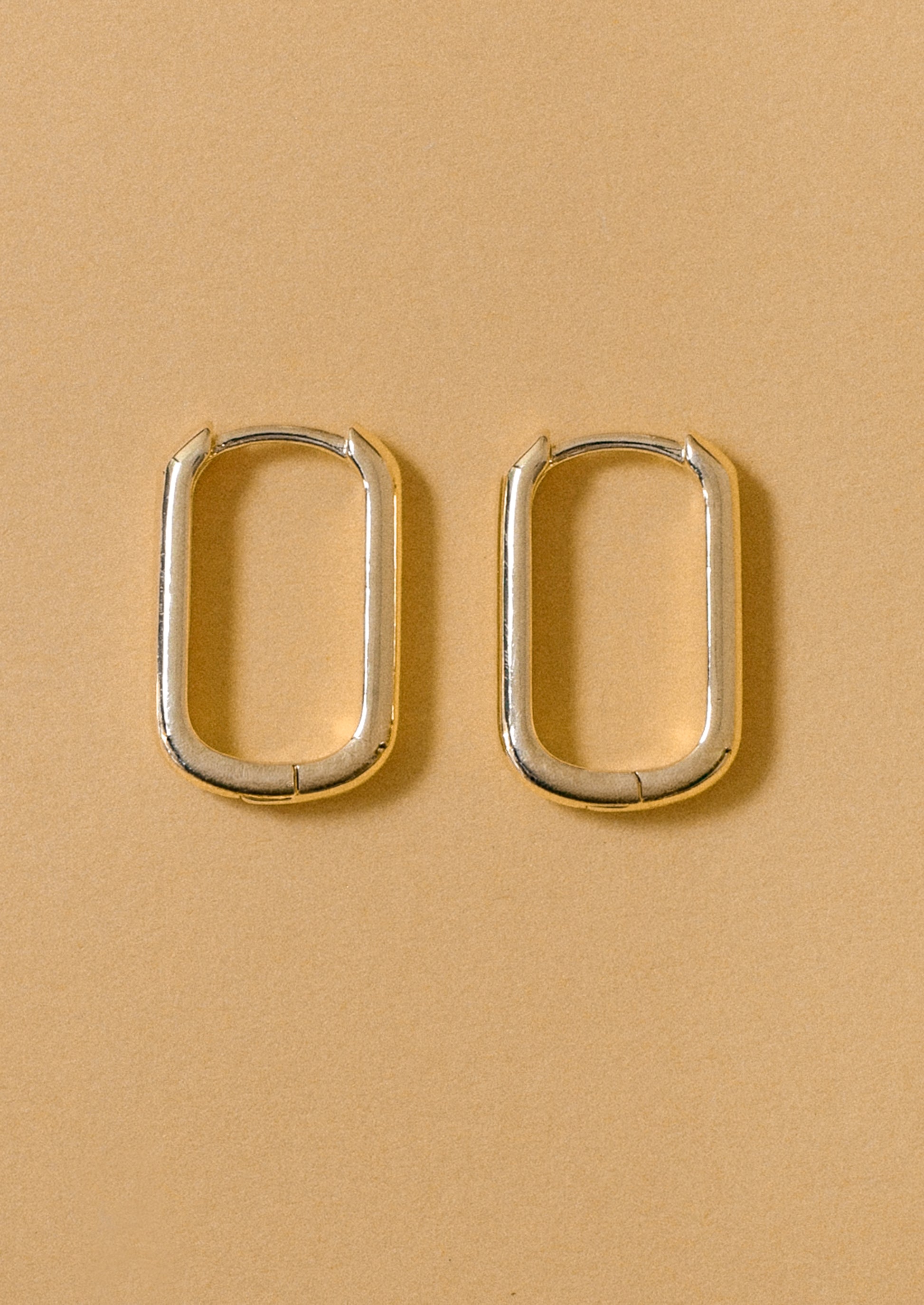 A pair of simple rectangular hoop earrings.