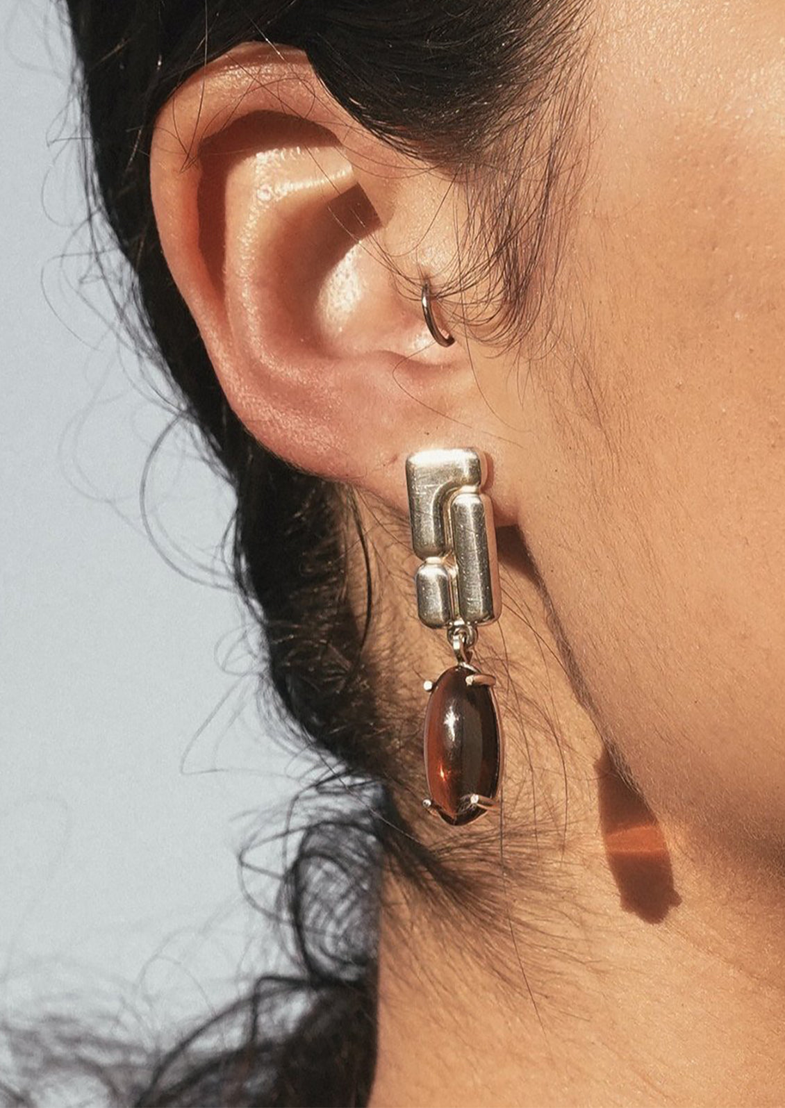 A pair of sterling silver drop earrings with brown glass cabochons.