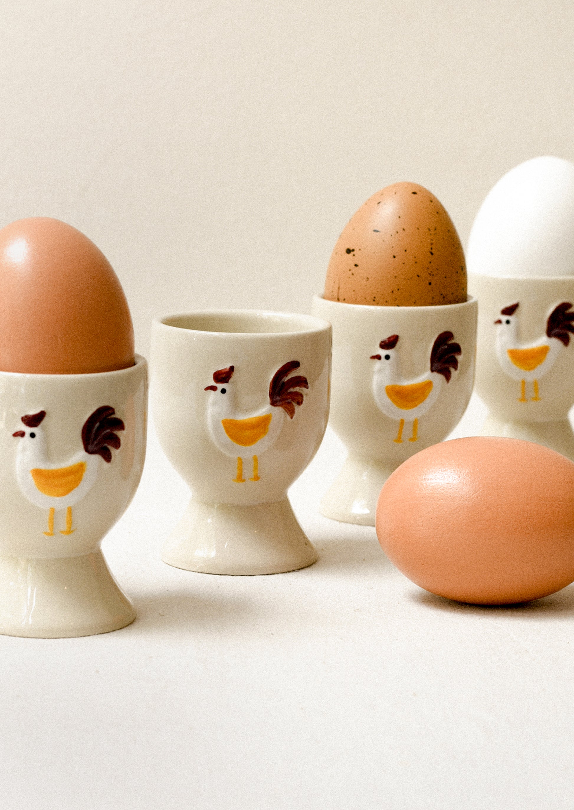 Egg cups with chicken design containing eggs on a light background