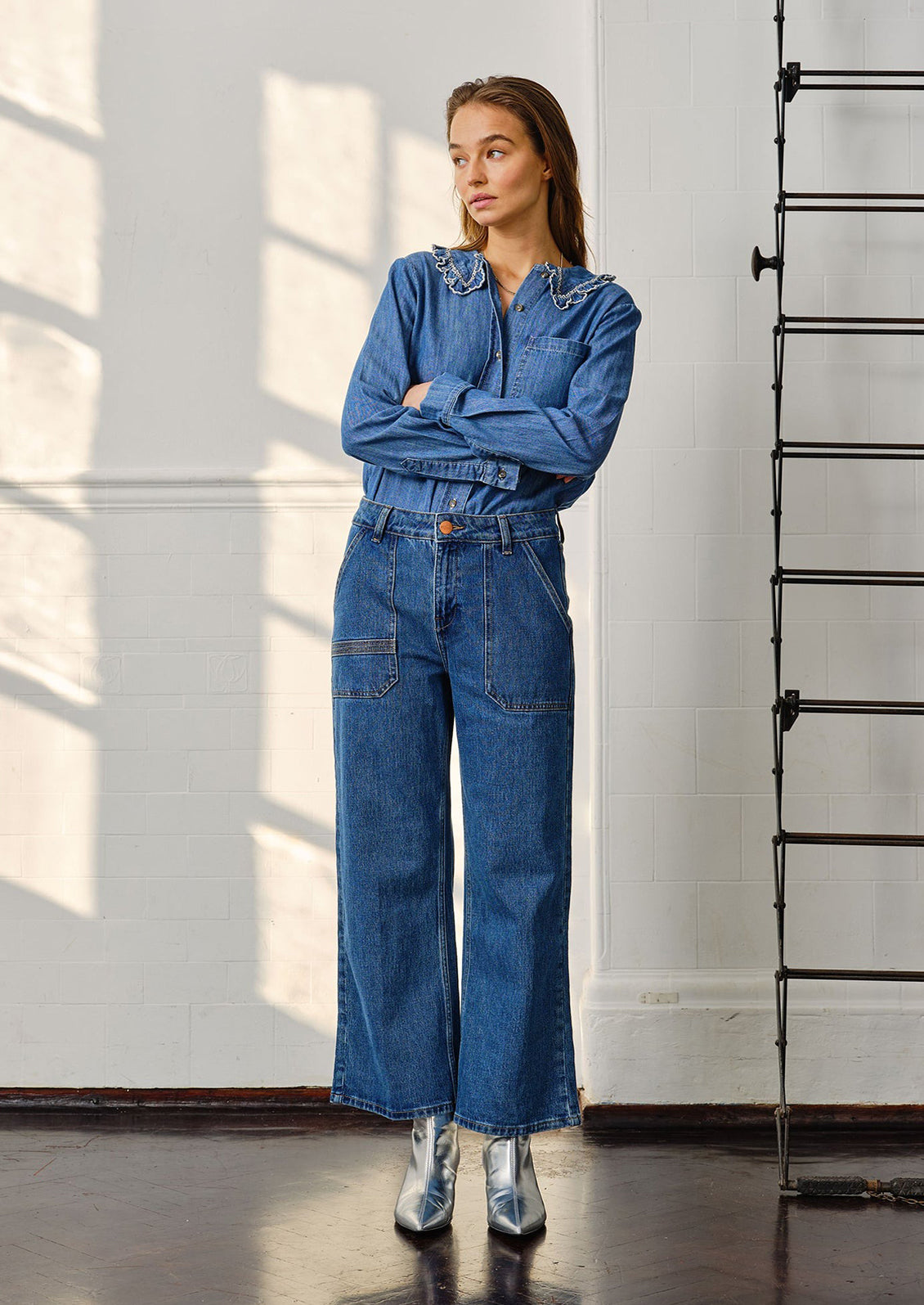 A woman wearing blue jeans with denim top and silver boots.