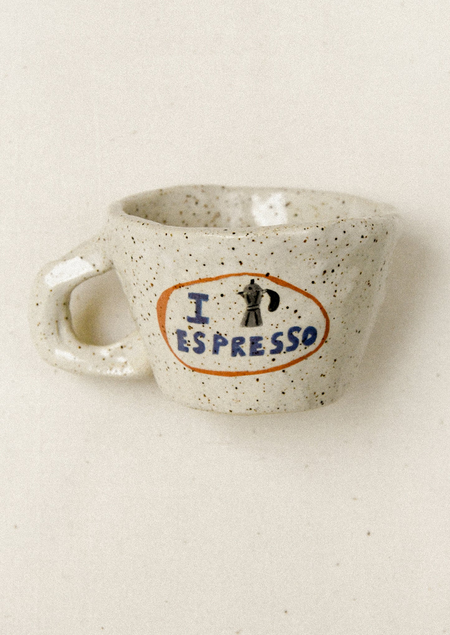 Speckled ceramic mug with 'I ❤️ Espresso' design on a beige background