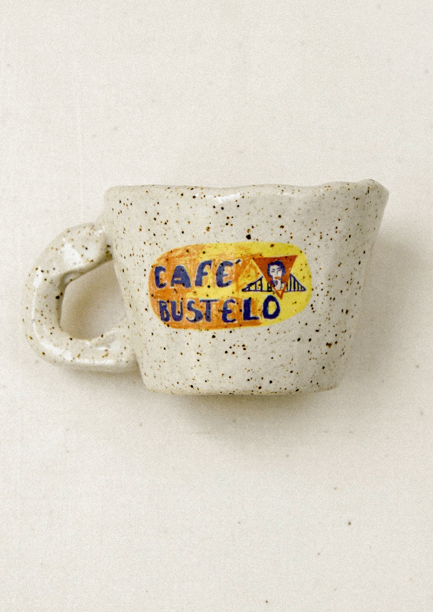 Speckled ceramic mug with 'Cafe Bustelo' logo on a light background