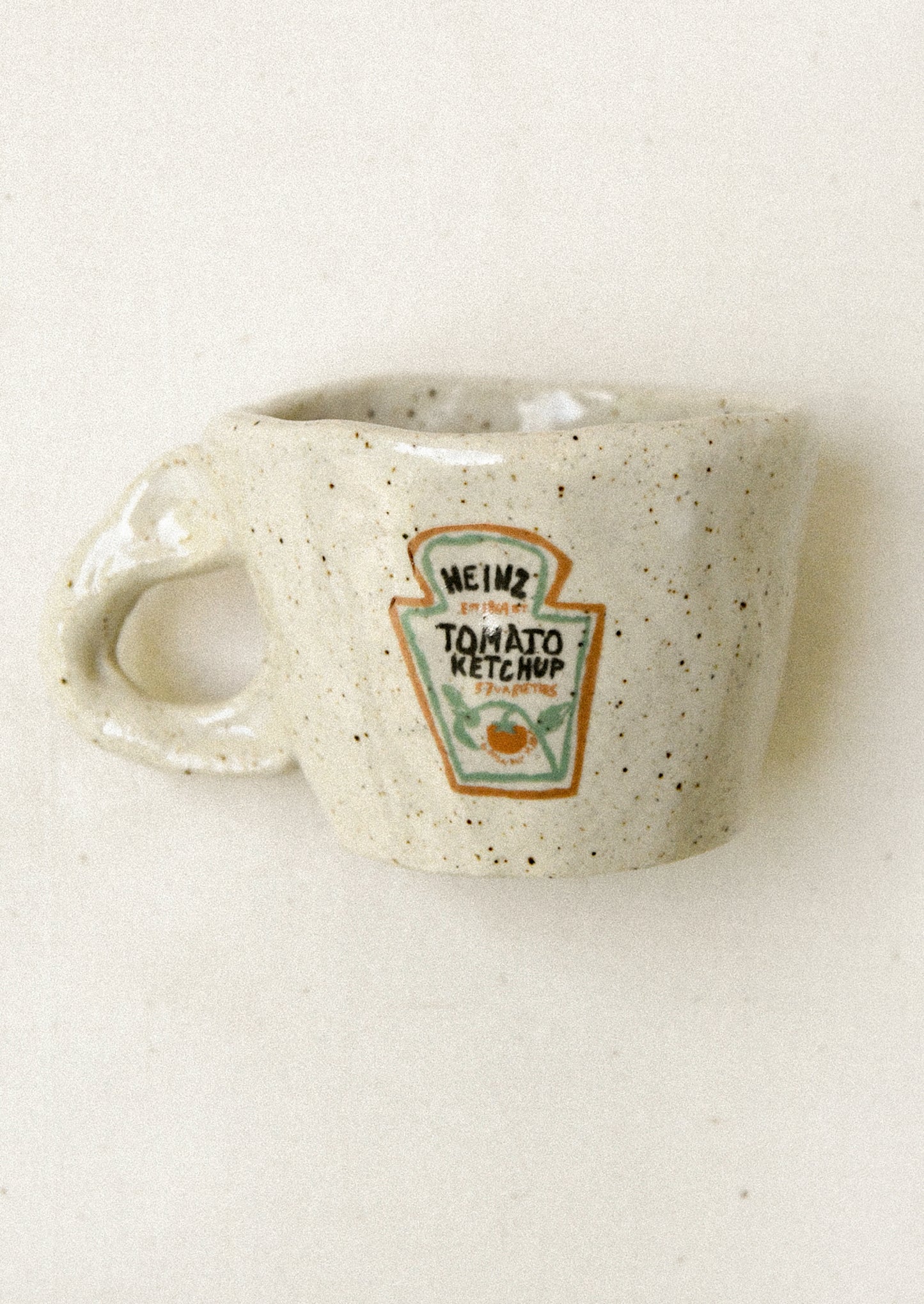 Speckled ceramic mug with Heinz Tomato Ketchup label design on a white background