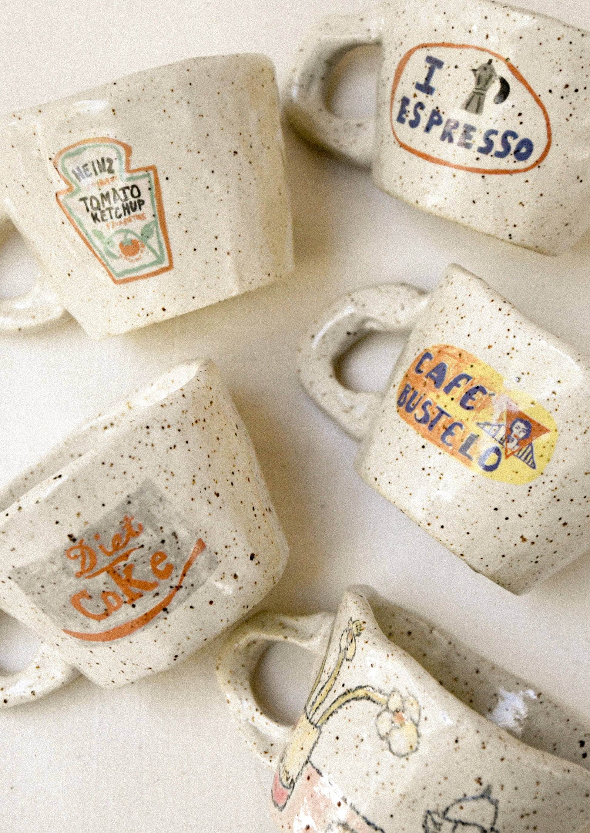 Speckled ceramic mugs with various prints on a white background