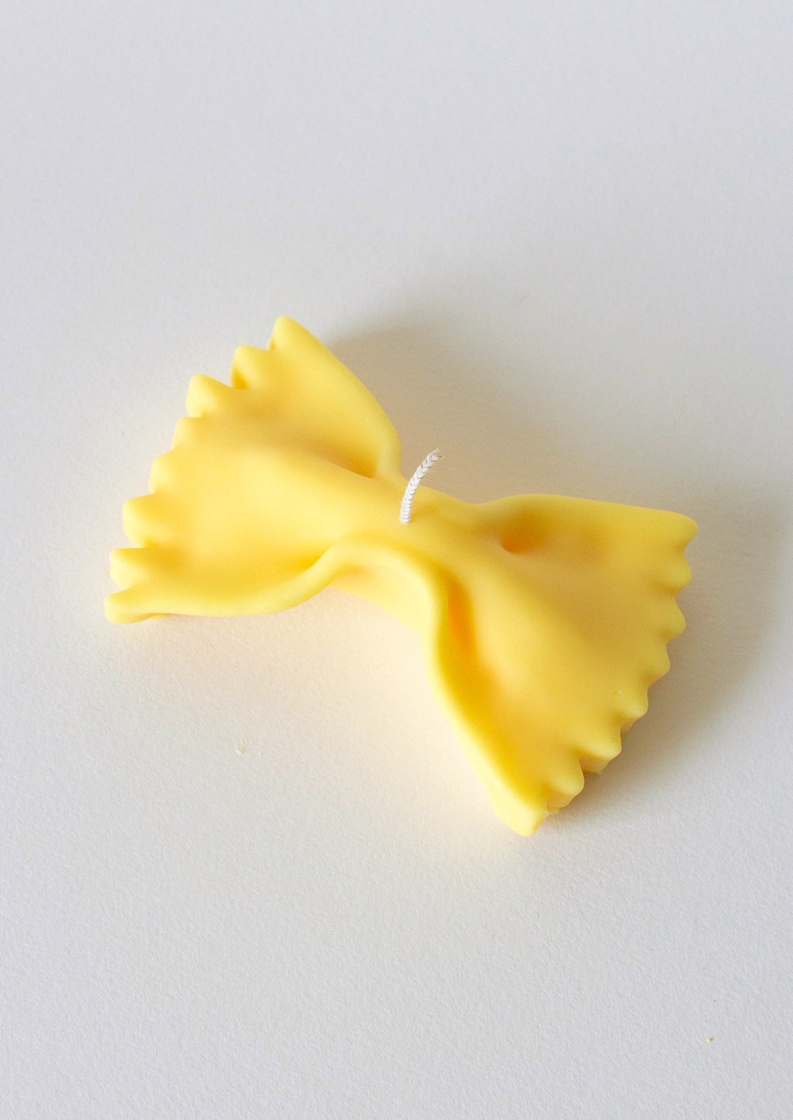 A candle in the shape of a piece of farfalle pasta.
