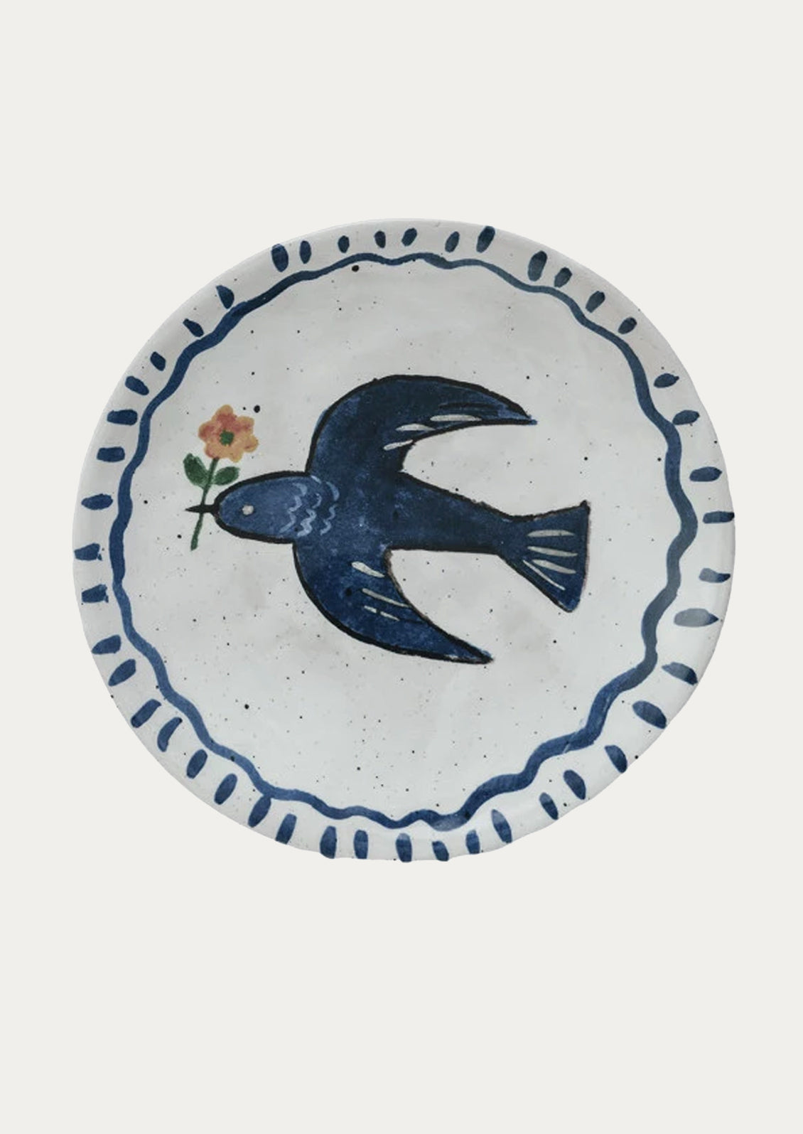 A small ceramic plate with hand painted imagery of blue bird holding flower.