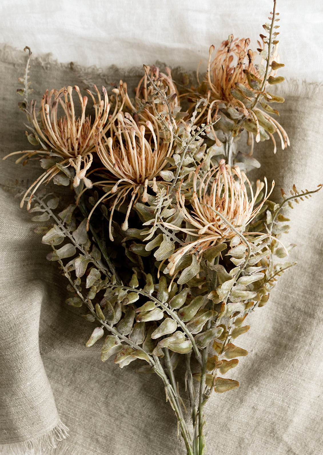 A faux floral spray in the form of blush colored pincushion flower.