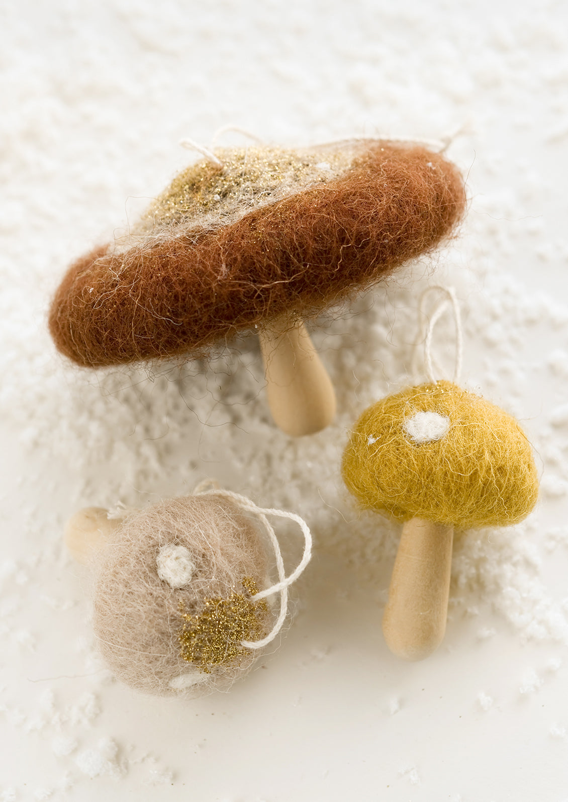Mushroom ornaments in assorted colors with felted tops and wooden "stumps".