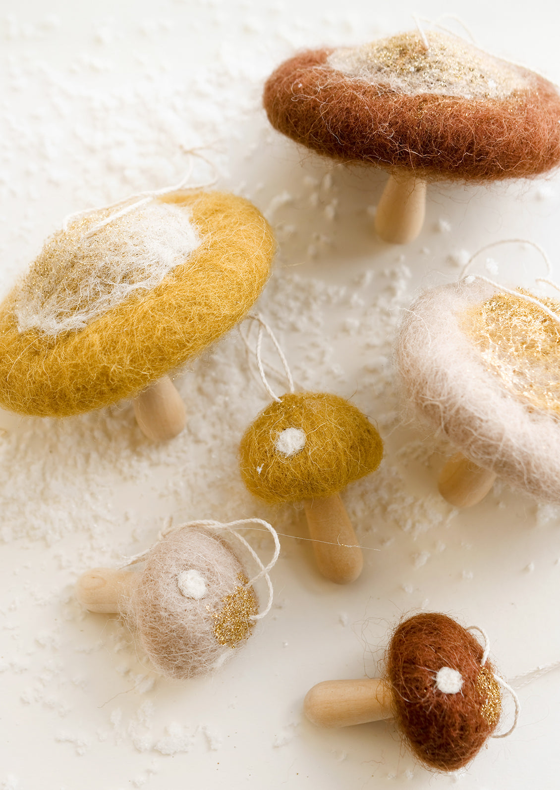 Mushroom ornaments in assorted colors with felted tops and wooden "stumps".