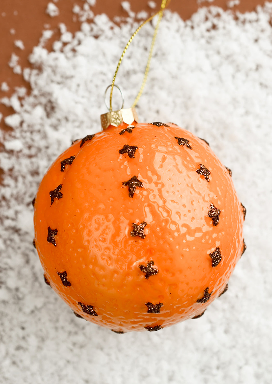 A glass ornament of a clove spiked orange.