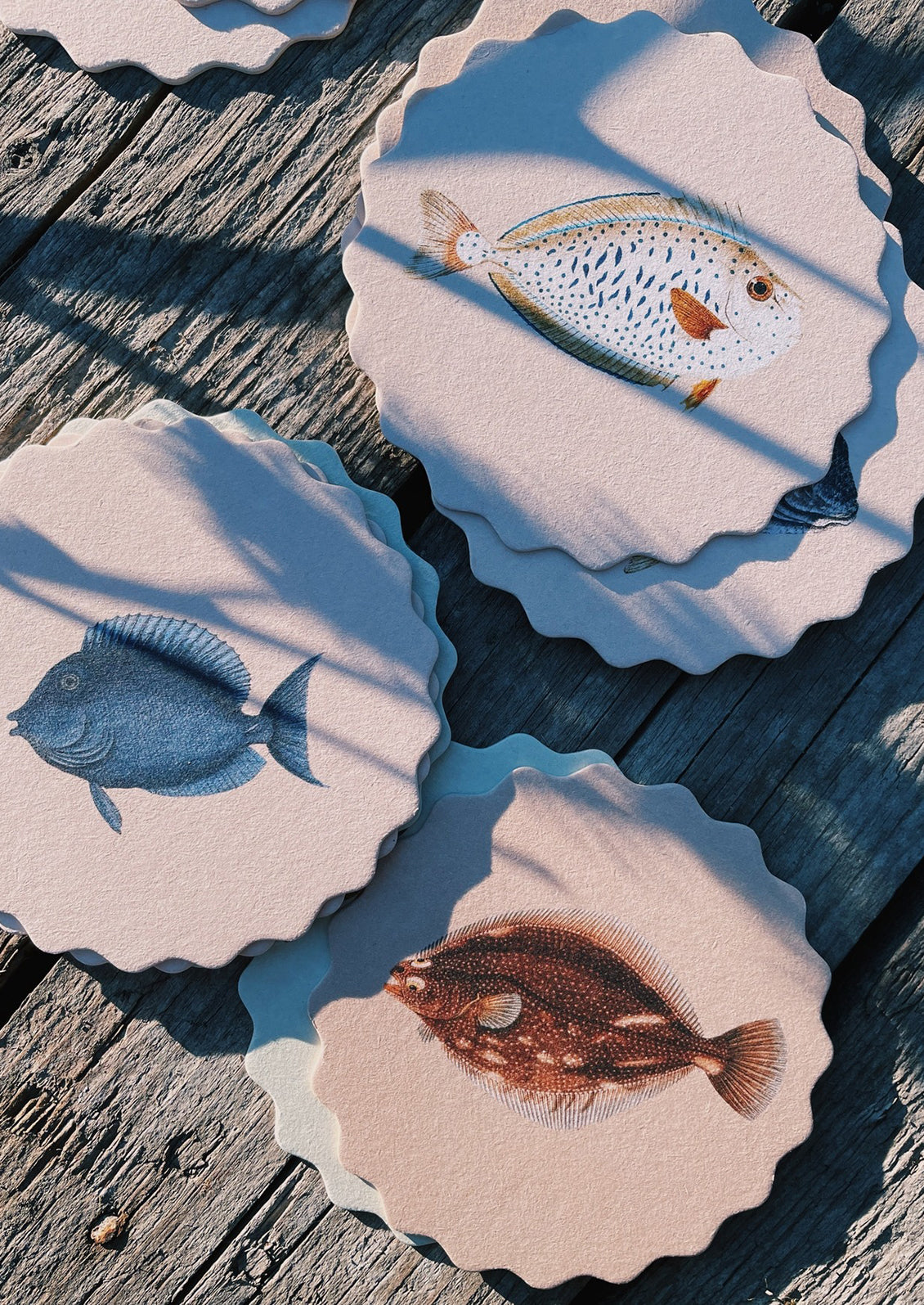 A set of scalloped edge paper coasters with 10 different fish prints.