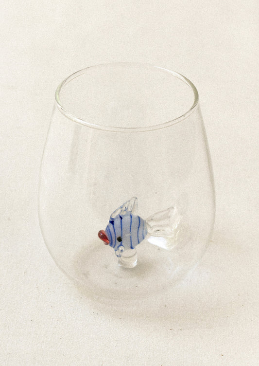 A clear tumbler glass with lampwork fish detail at inner bottom.