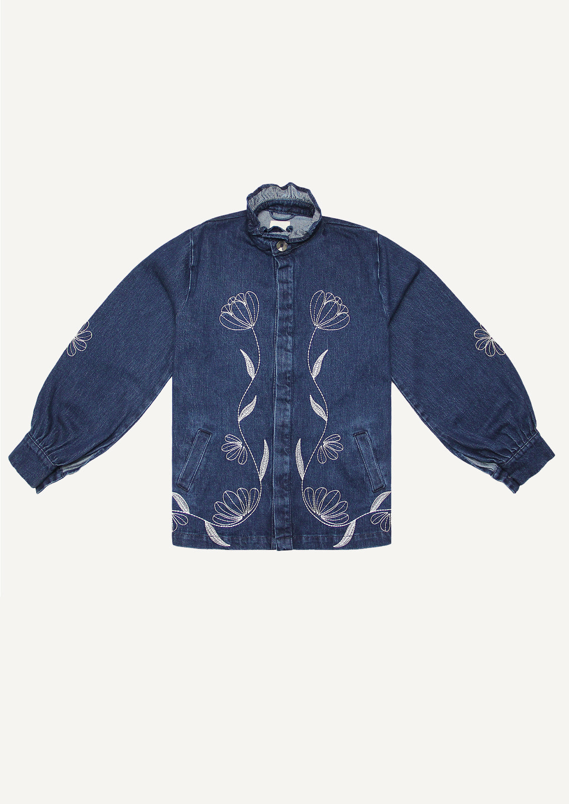 A woman wearing a blue denim jacket with white floral embroidery.