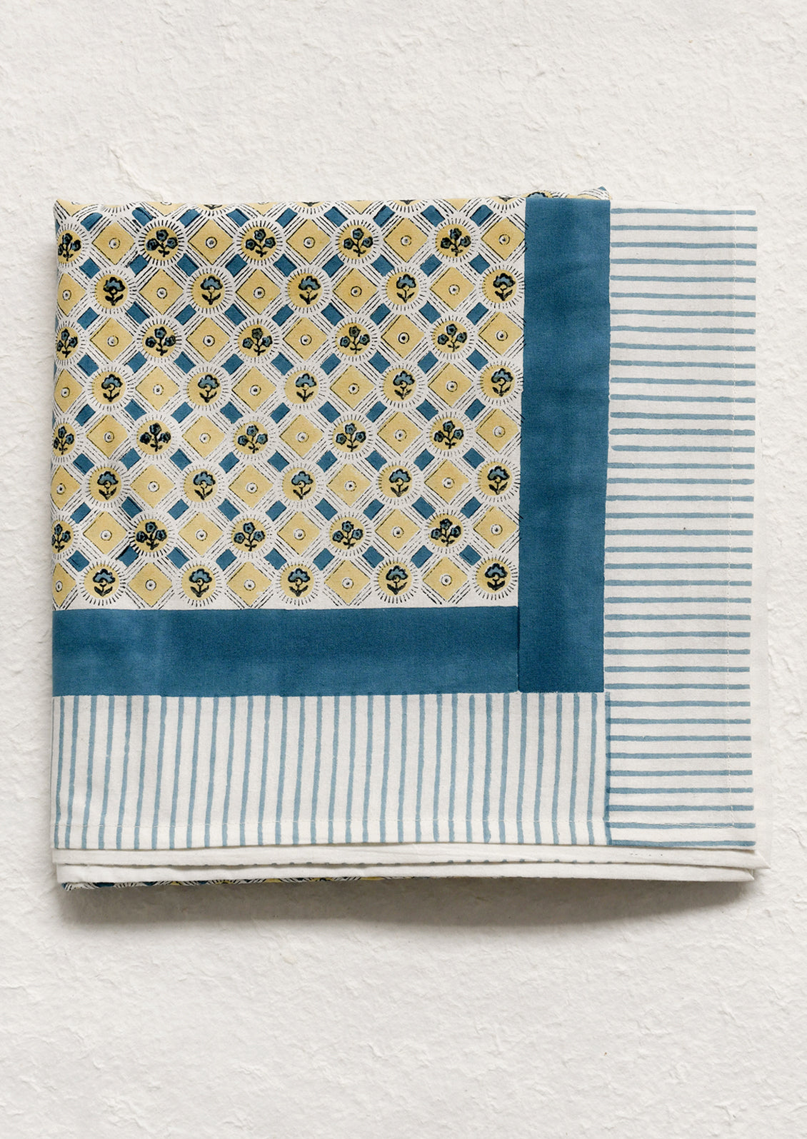 A tablecloth in blue and yellow floral print with striped border.
