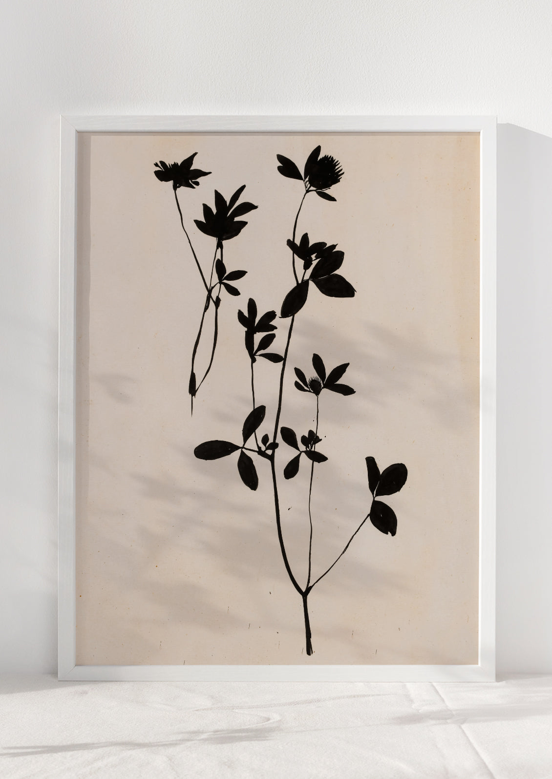 An art print of black silhouetted flower on beige background,framed.