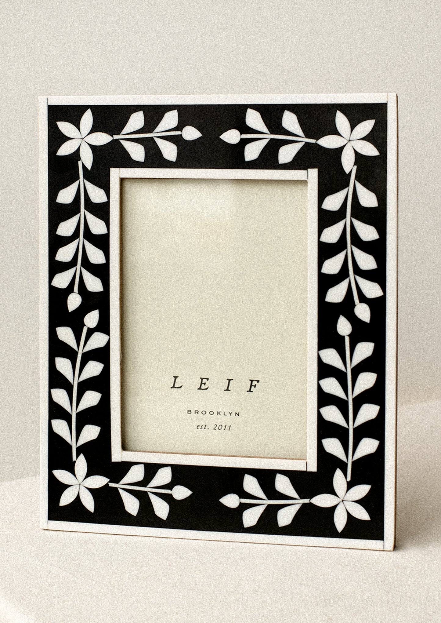 A black and white inlay frame with flower pattern.